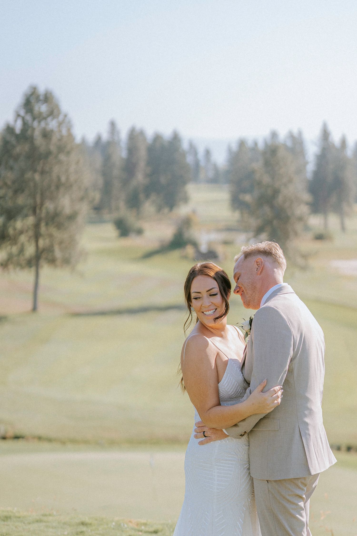 A couple shares an intimate moment on a sunny golf course during their wedding photoshoot.