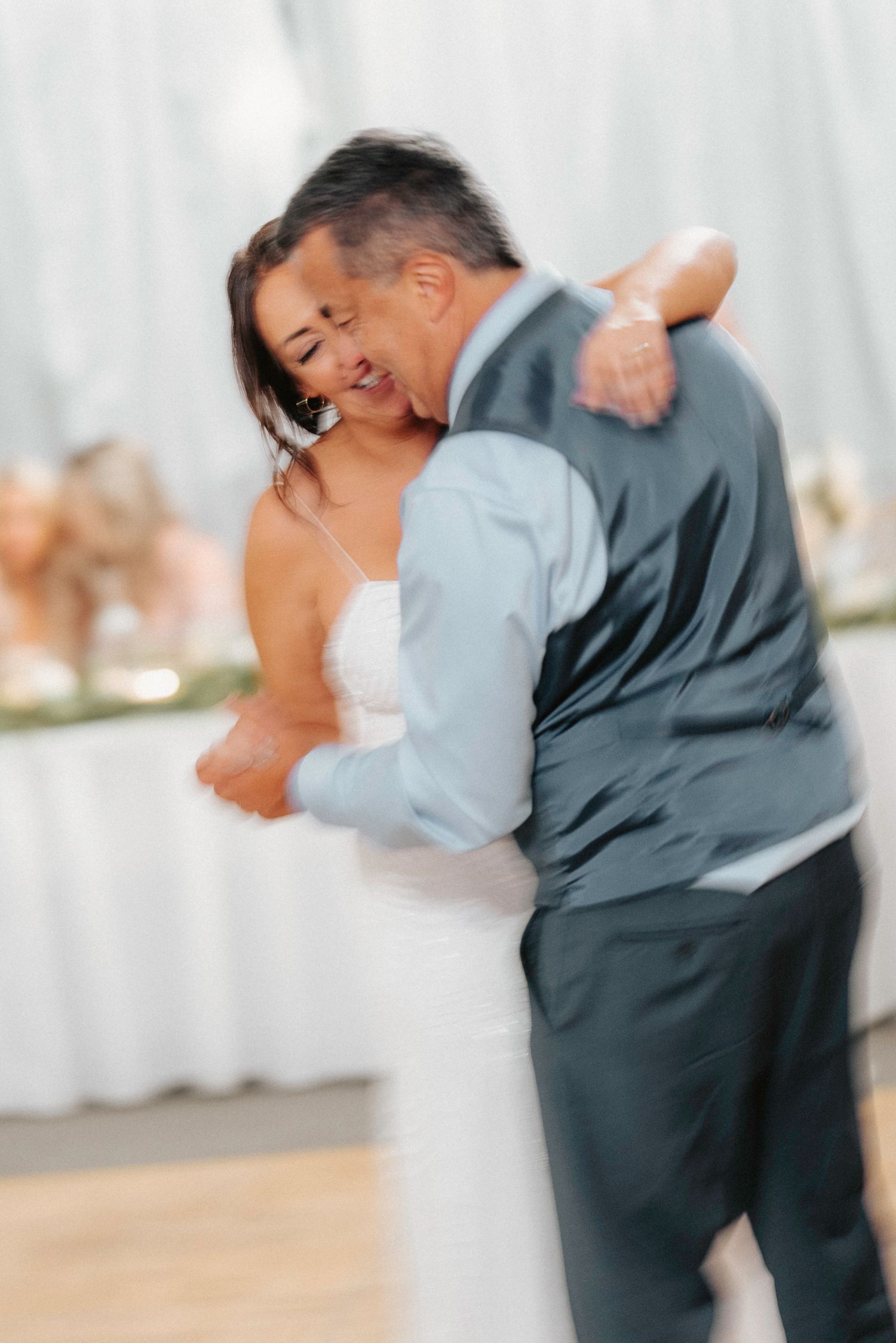 Wedding couple dances energetically in a white-draped reception space during their celebration.