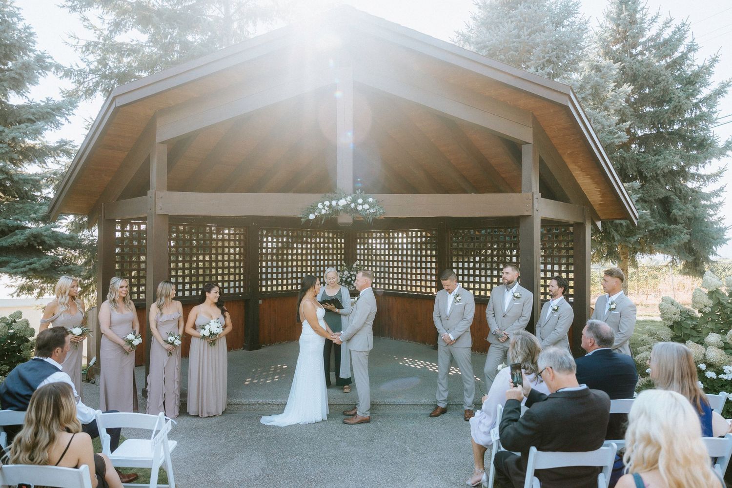 Panoramic sequence of an outdoor wedding ceremony under a wooden gazebo surrounded by tall evergreen trees at sunset.
