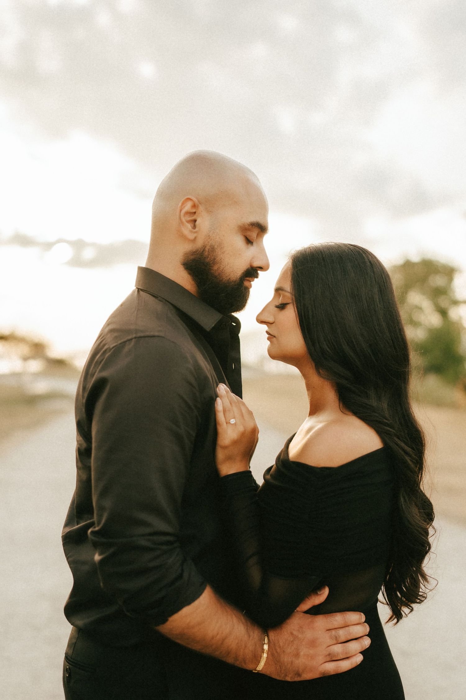 A couple in black outfits share intimate moments in a series of romantic outdoor portraits at sunset.