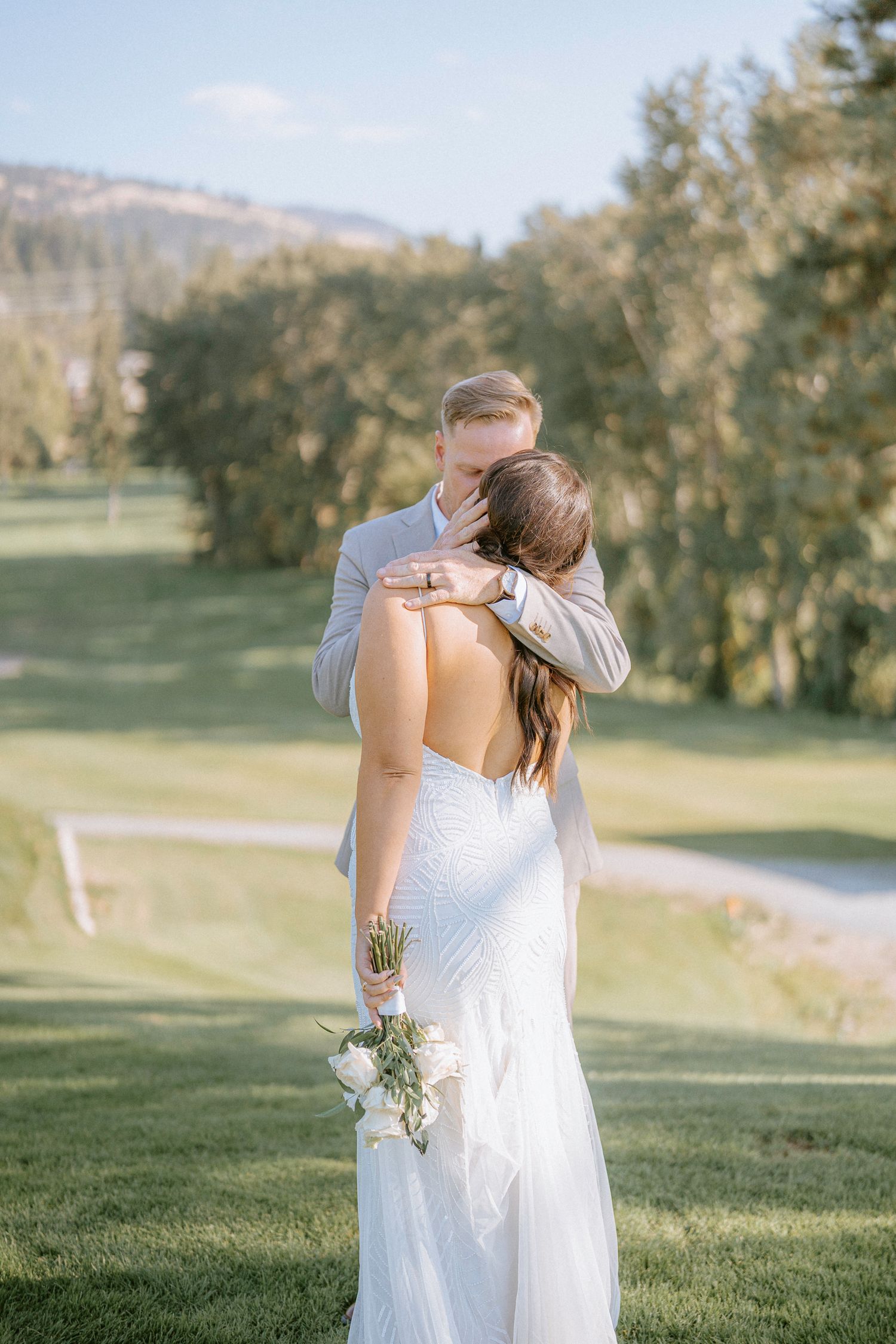 Romantic wedding photography session on a lush green hillside with mountain views.
