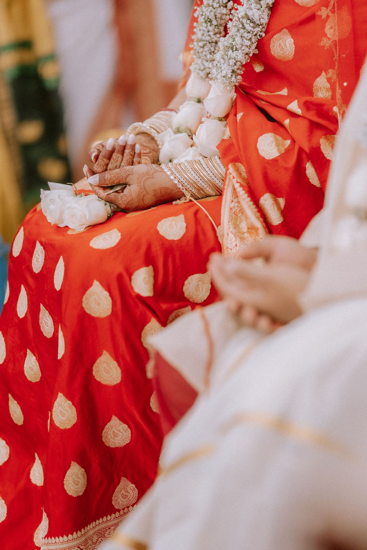 Close-up details of a red and gold patterned sari with intricate embroidery and traditional jewelry.
