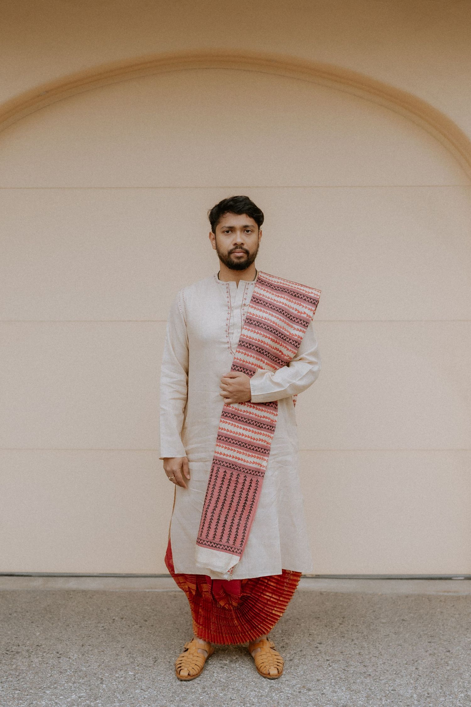Traditional Indian attire with red and white textiles displayed against a neutral beige wall.