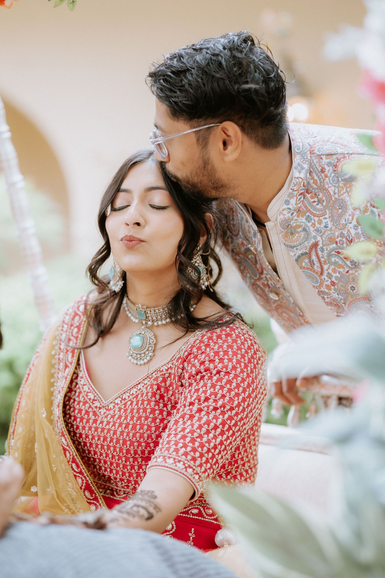 Couple in traditional Indian attire sharing an intimate moment during an outdoor wedding photoshoot.