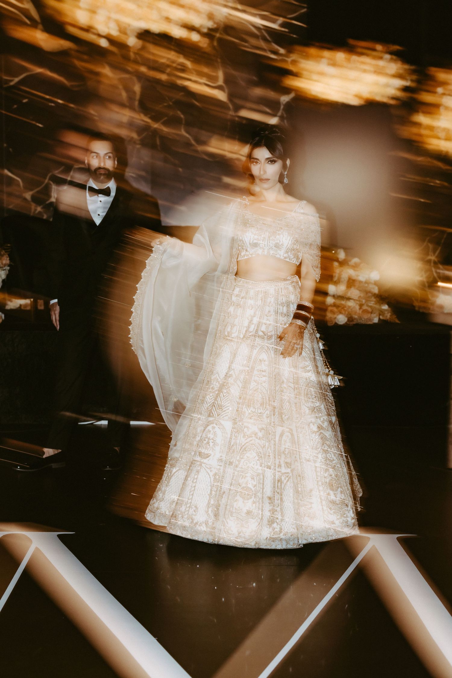 Motion-blurred artistic wedding photography captures ethereal dance movements in a dimly lit reception venue.