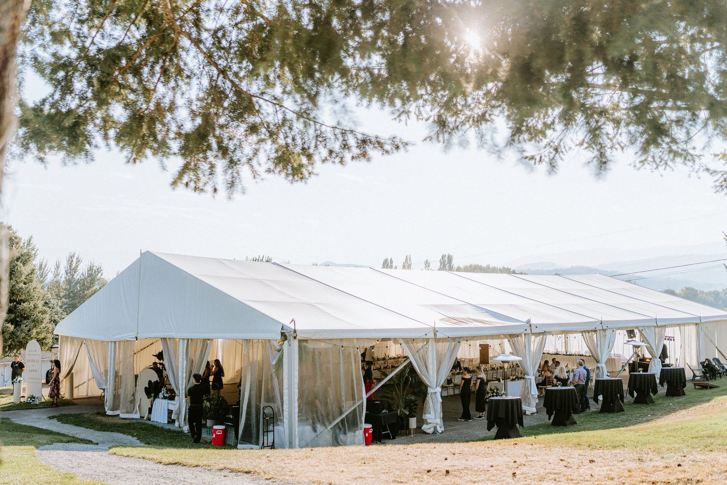 Large white wedding reception tents set up on a scenic hillside venue.