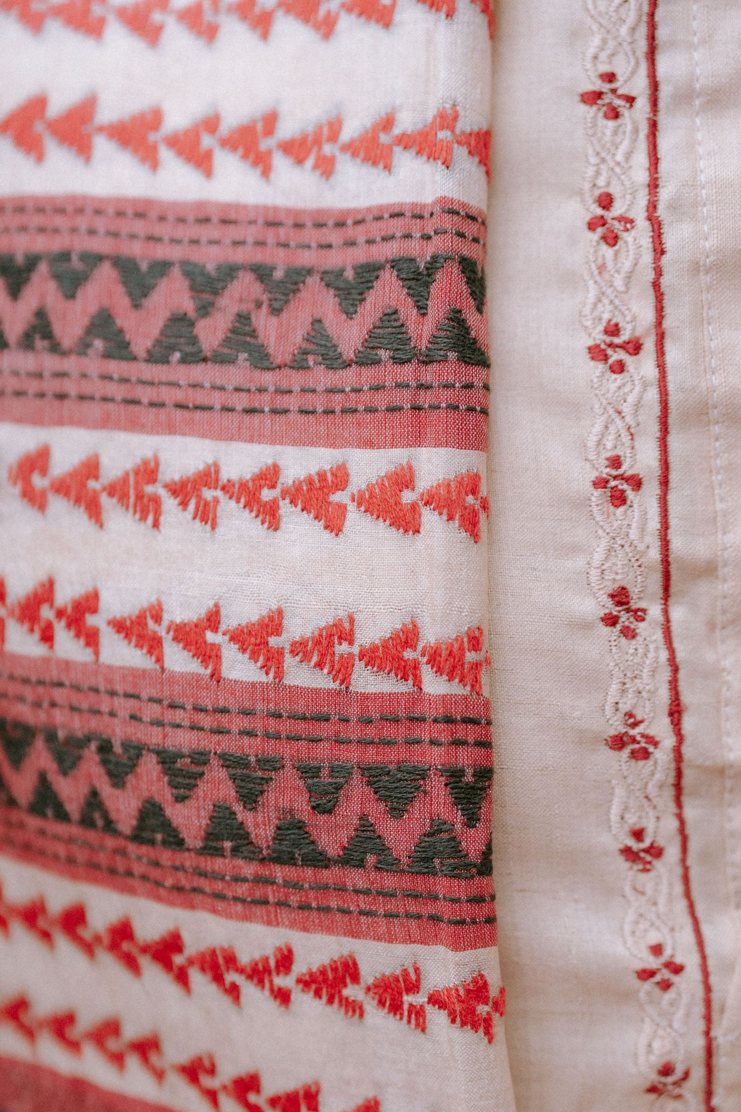 Close-up view of traditional Ukrainian embroidery pattern featuring red and gray geometric designs on white fabric.