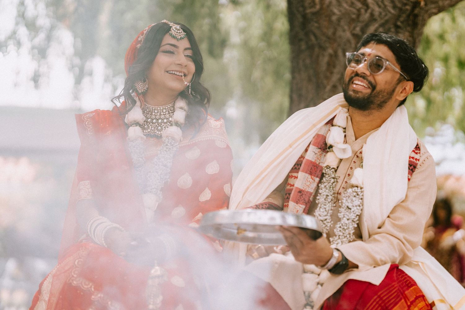 Outdoor wedding celebration with soft natural lighting and festive pink smoke effects.