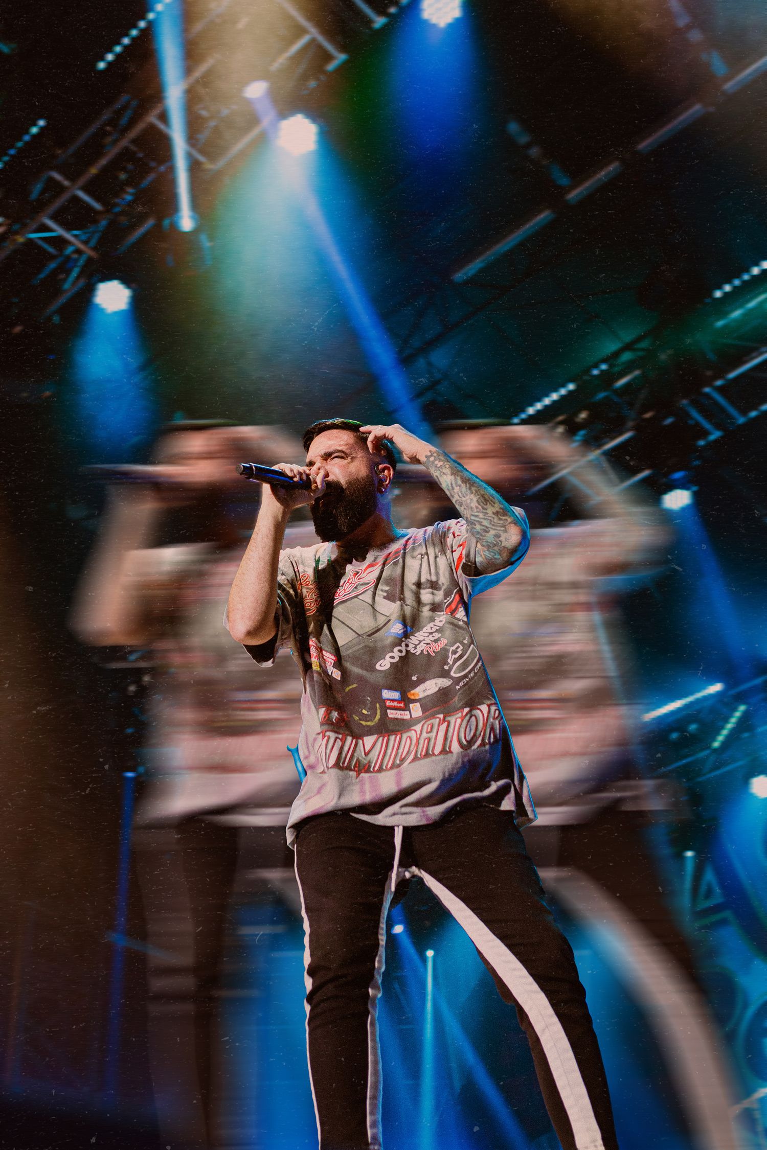 Dynamic concert performer leaps across stage under dramatic blue lighting during energetic live show performance.