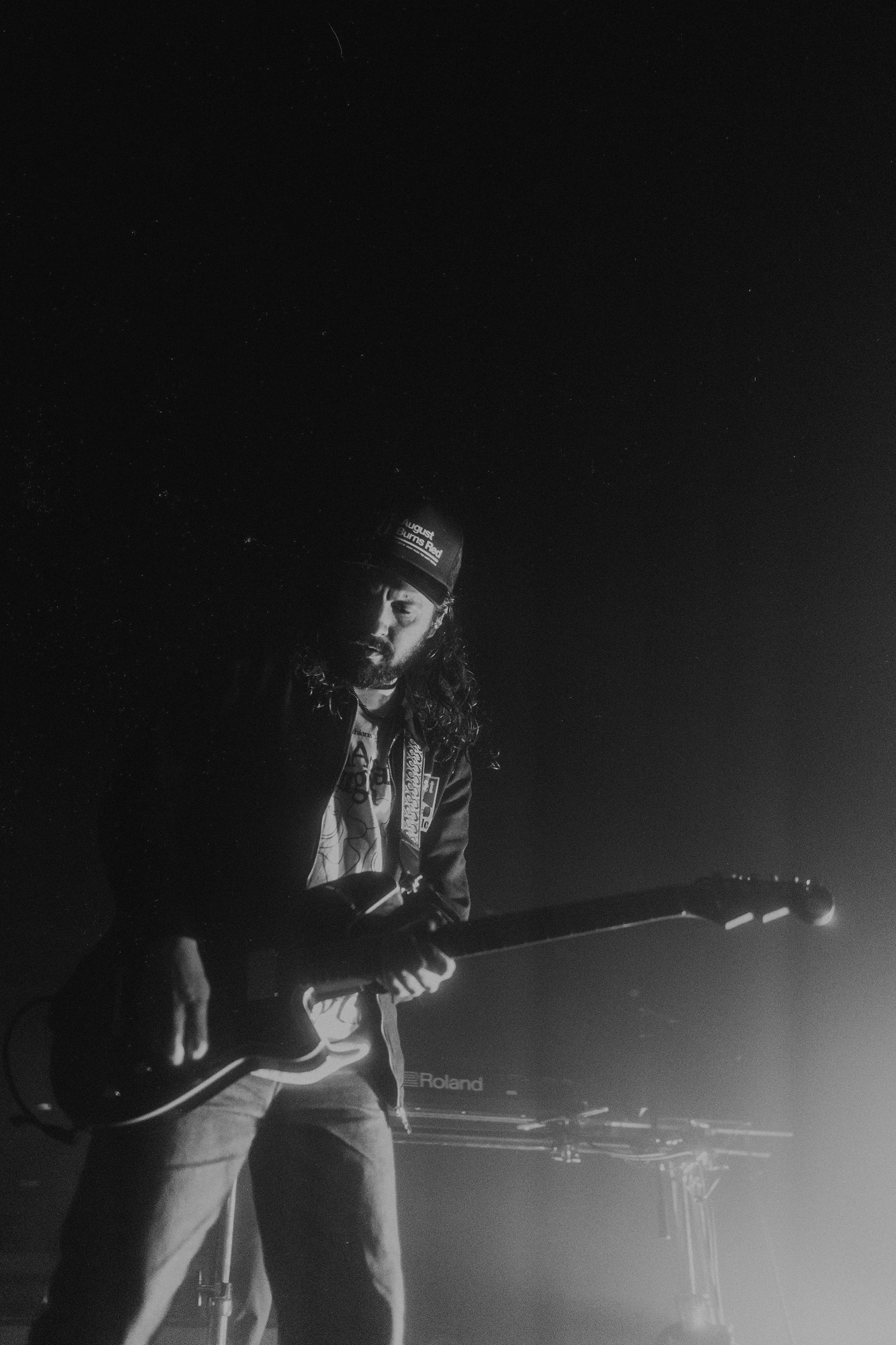 Dark concert photography capturing musicians performing with moody backlighting.