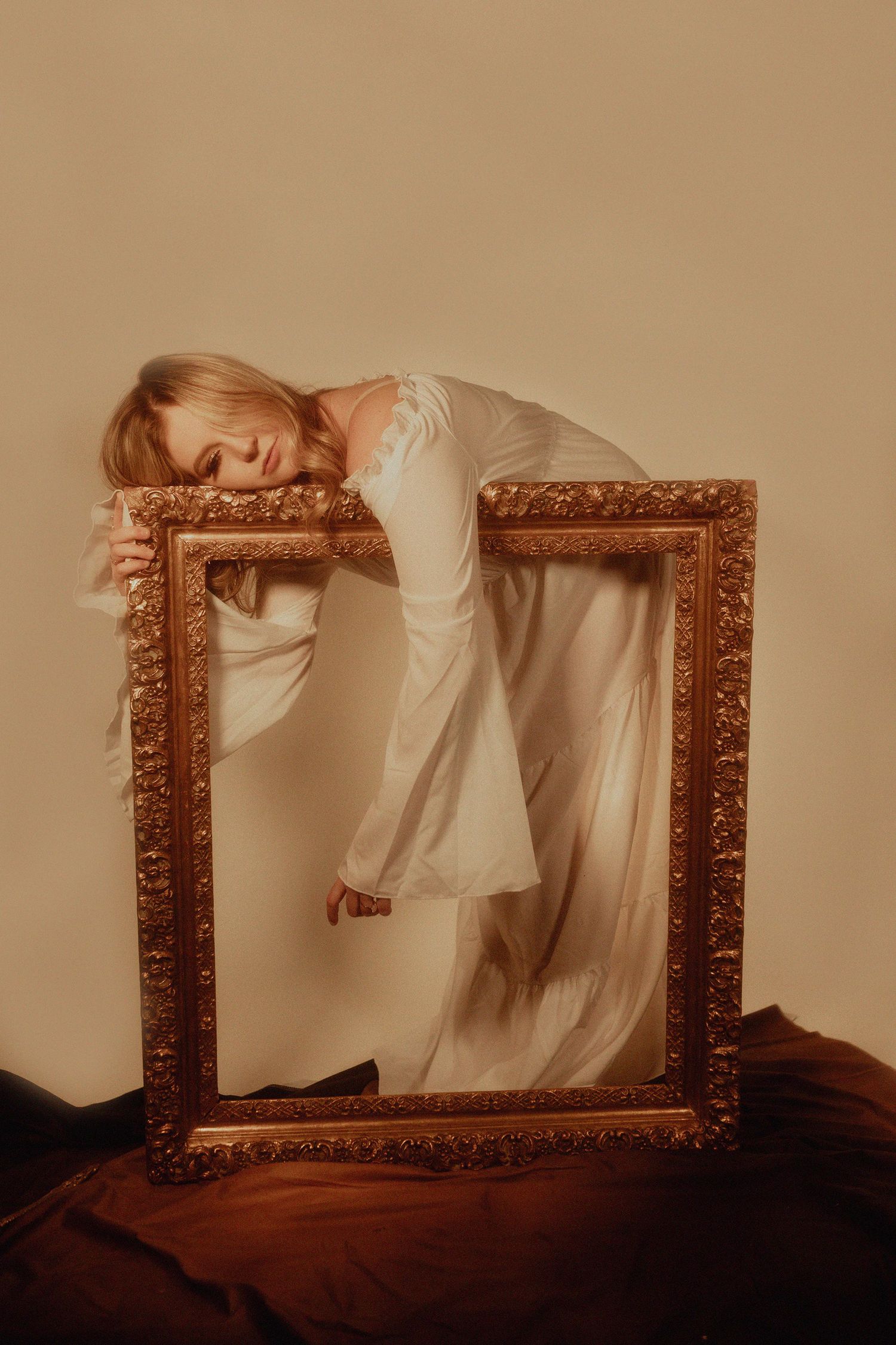 Creative portrait series with antique gold frame against beige background.