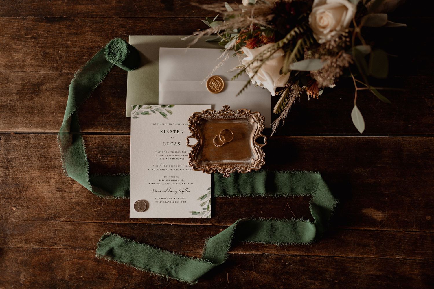 Wedding invitations and details laid out on a rustic wooden surface.