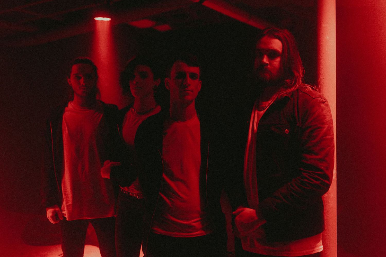 Group silhouettes illuminated by dramatic red lighting in dark setting.