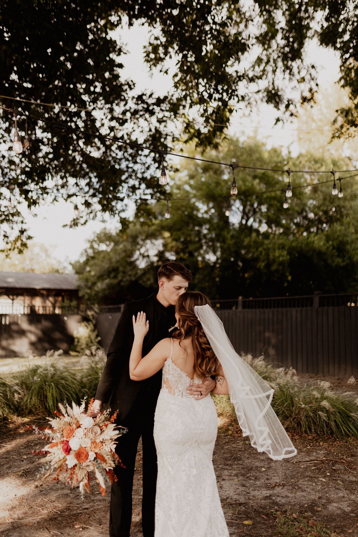 Outdoor wedding portrait featuring natural lighting and pampas grass decorations.