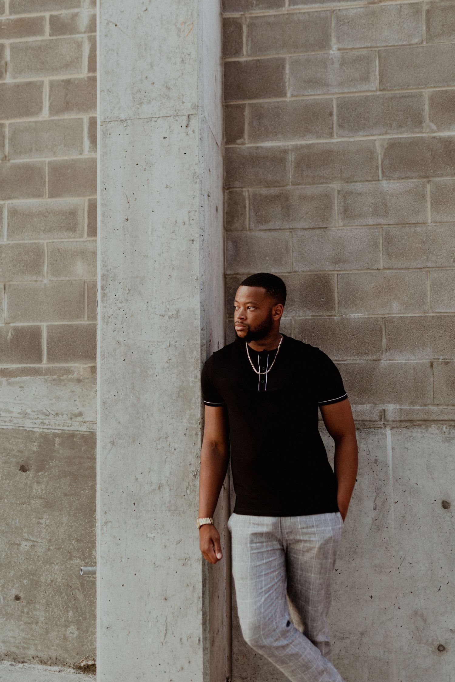 Urban portrait series against concrete columns and brick wall background.