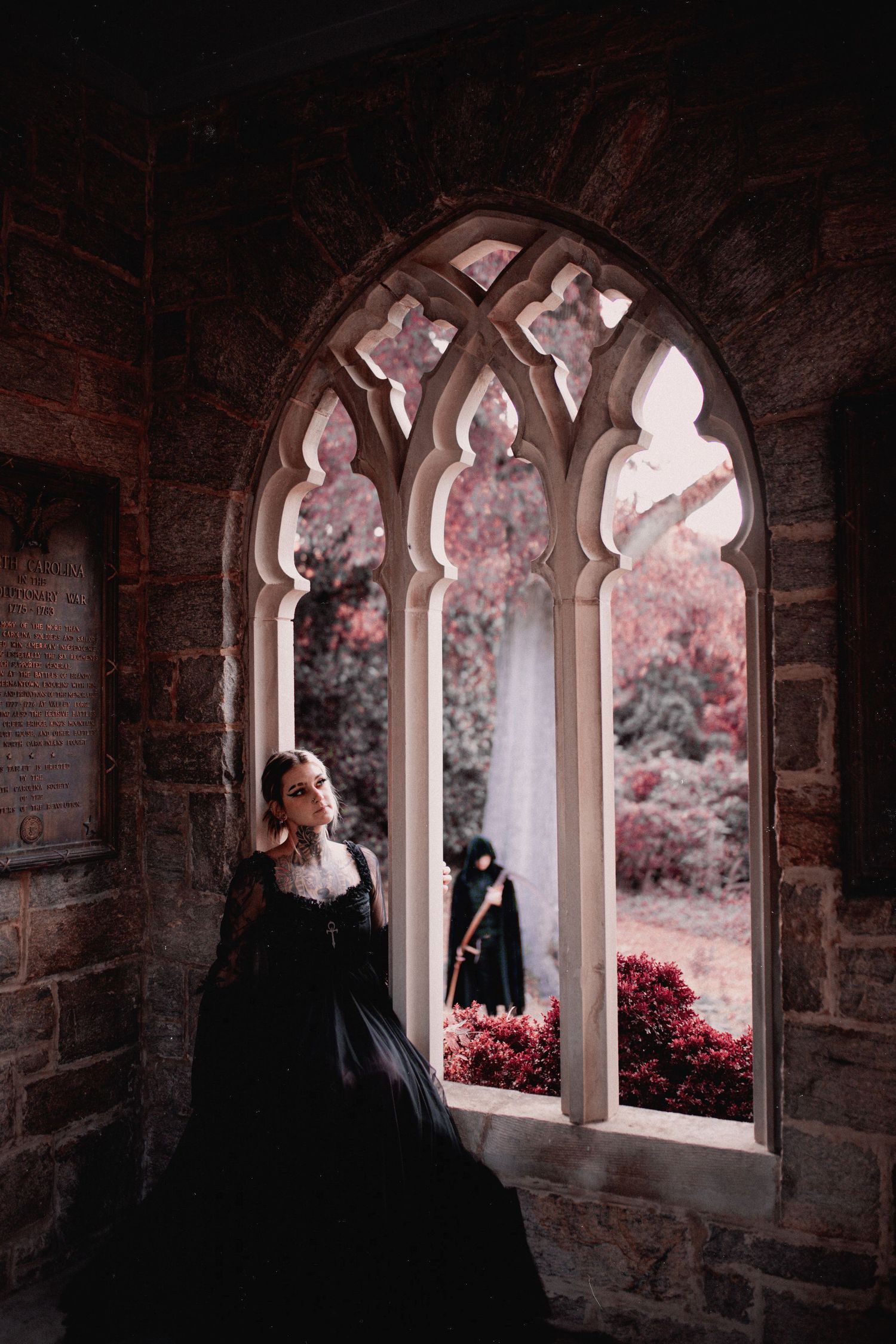 Gothic arched windows in stone wall frame dramatic view of pink flowering garden.