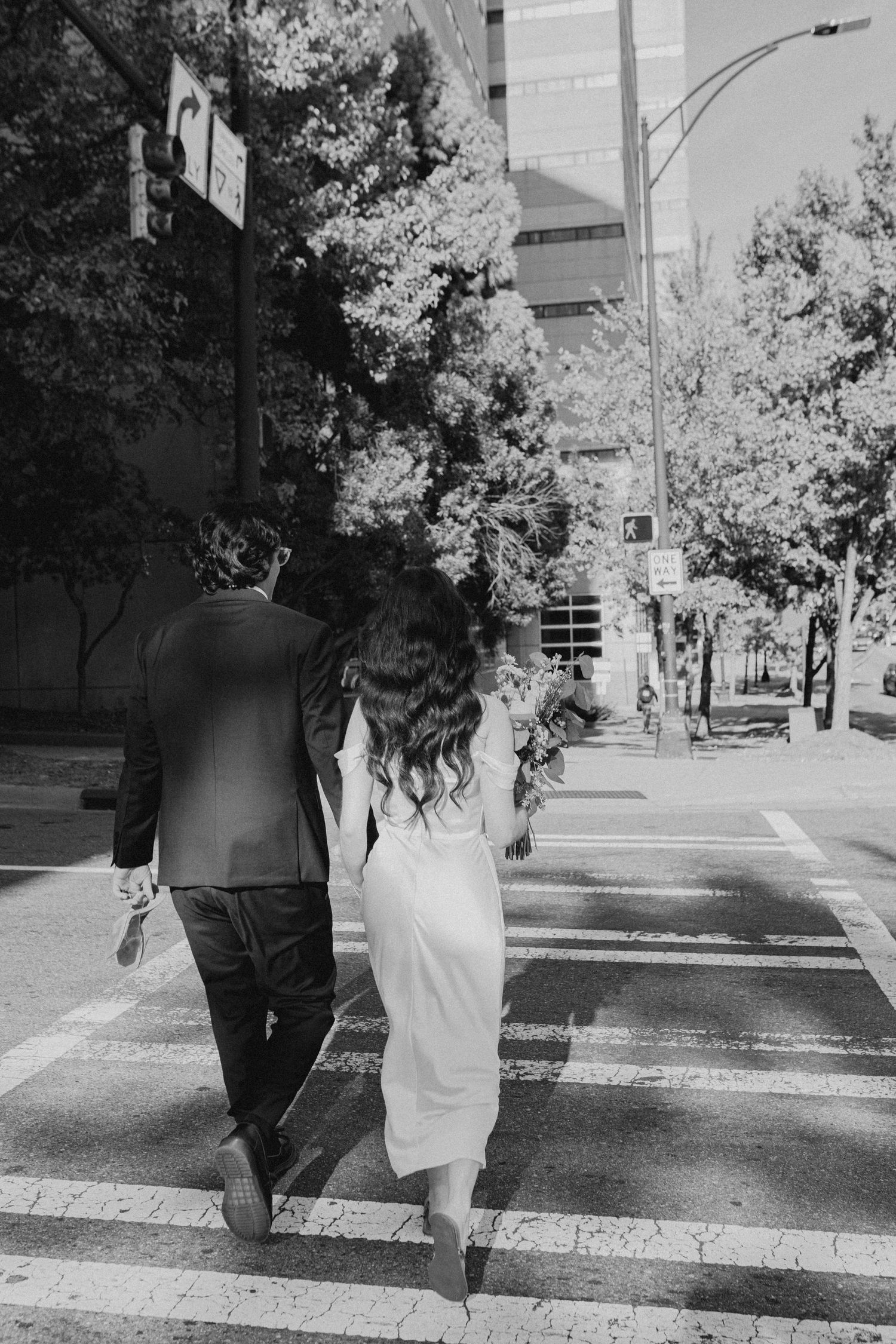 Black and white sequence of a couple walking together on a tree-lined street.