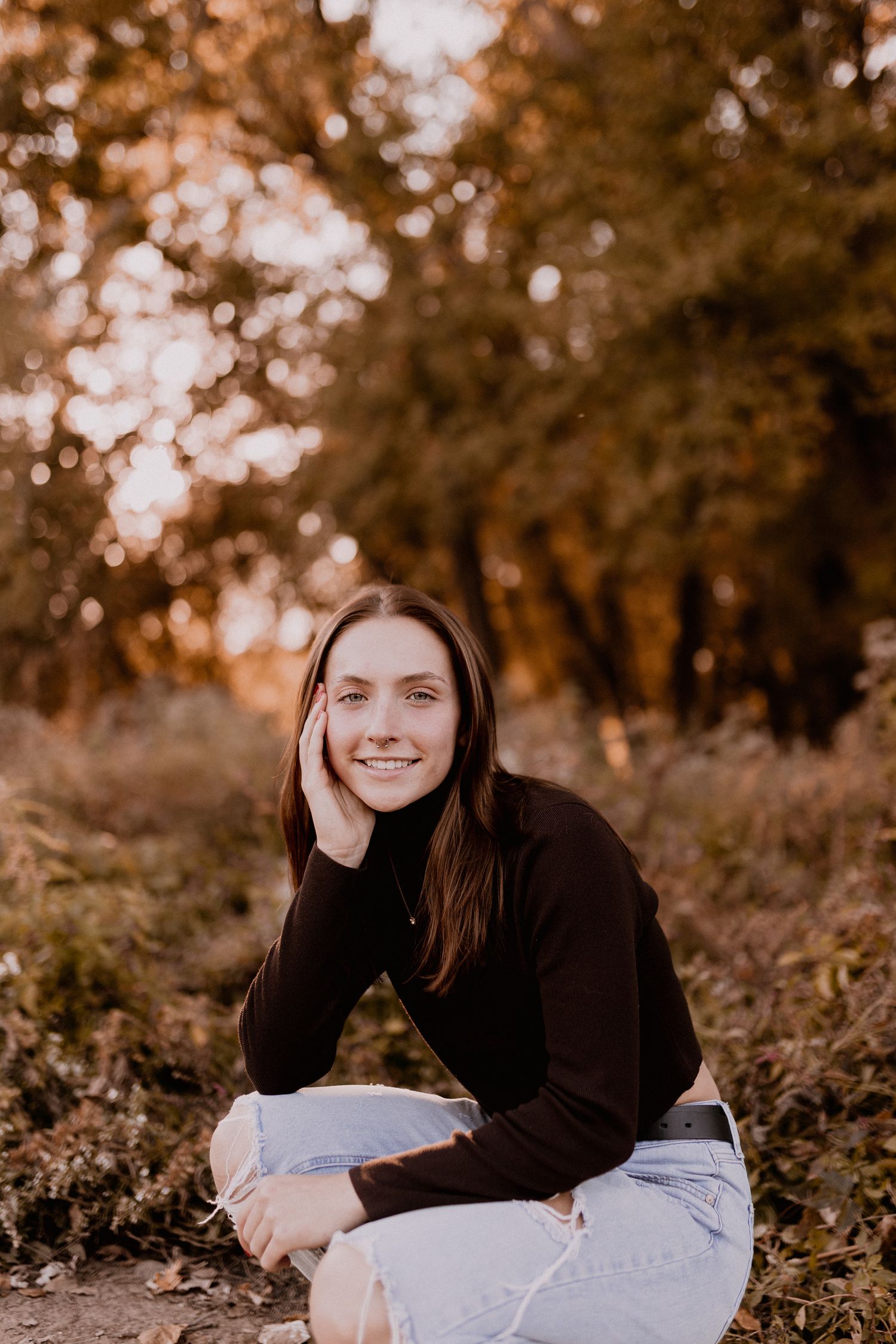 Autumn portrait session in a park with fallen leaves and warm golden lighting.