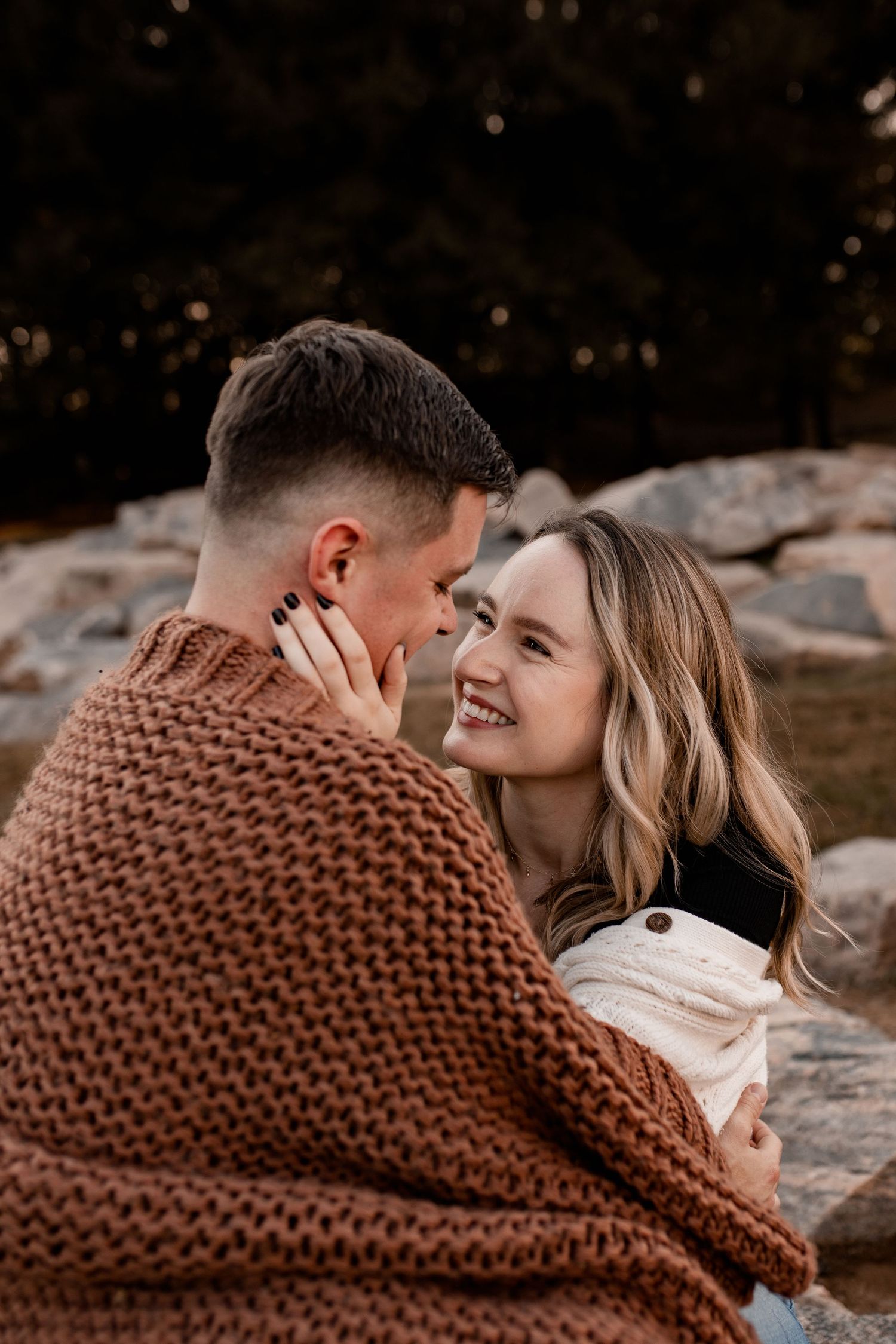 A cozy autumn scene with a chunky knit brown blanket against rocky terrain.