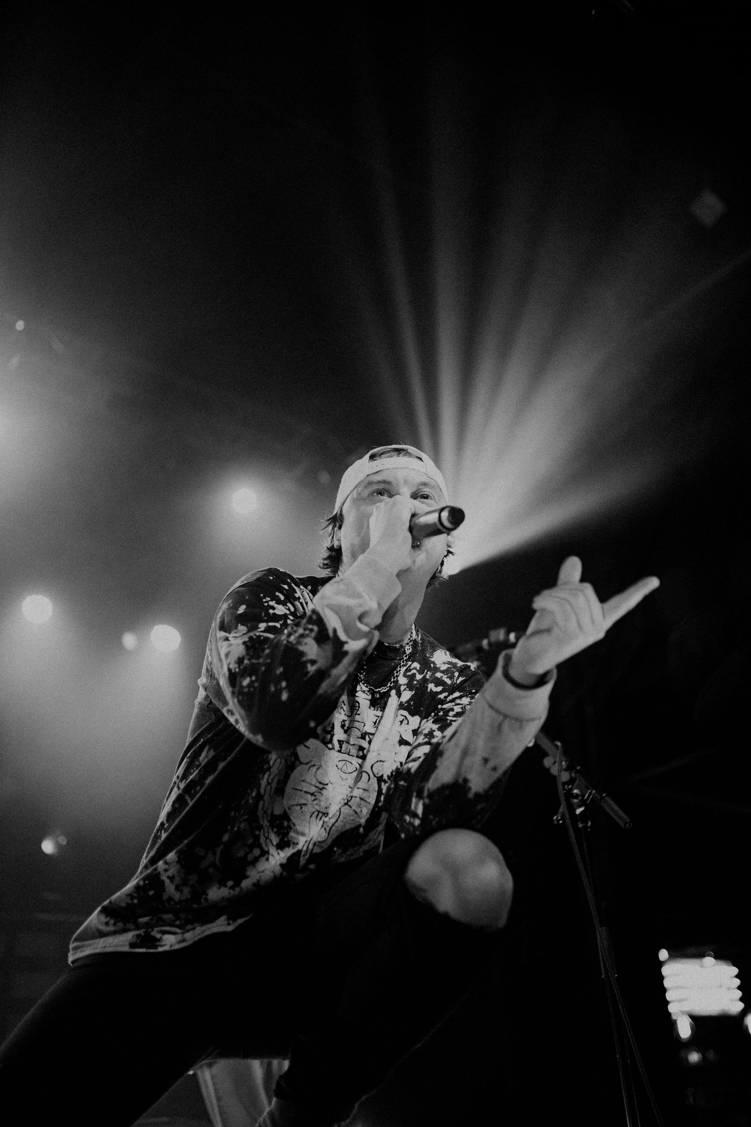 Dramatic black and white concert photography with striking light beams cutting through darkness.