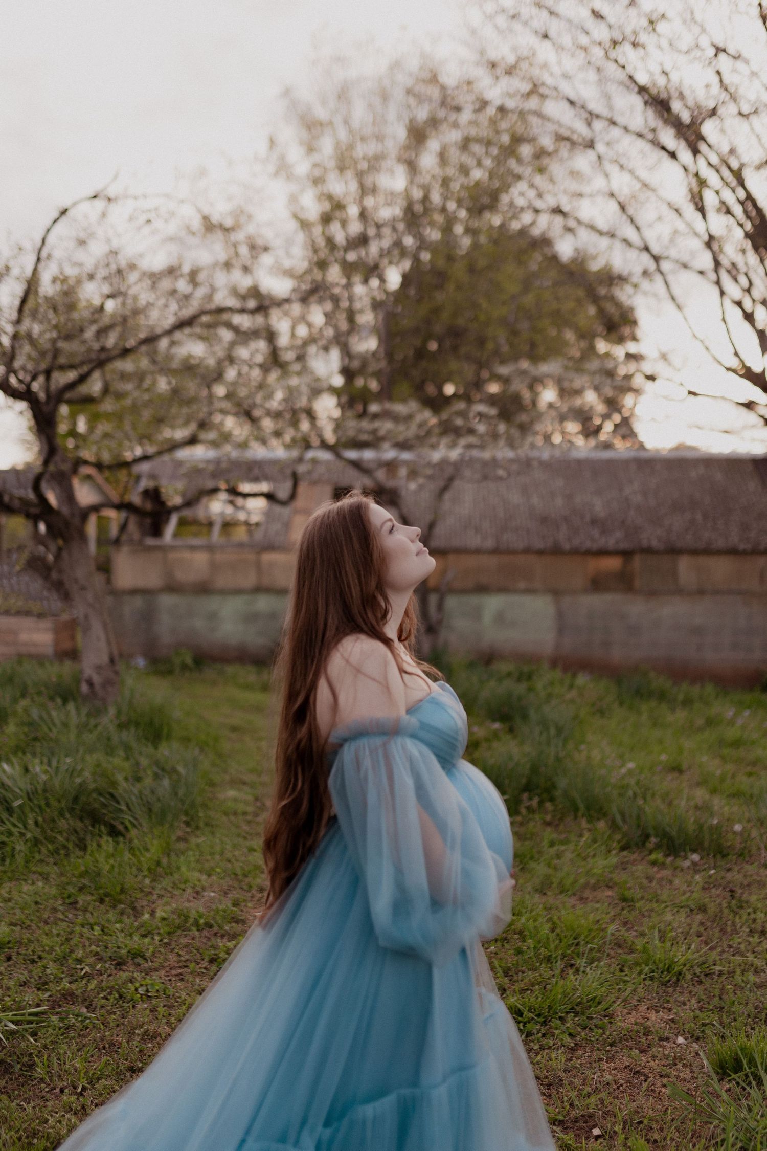 A dreamy scene of figures in light blue tulle gowns twirling in a rustic outdoor setting.