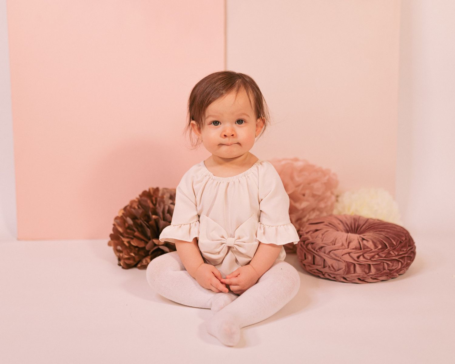 Baby photography session with soft pink backdrop and brown tulle decorations.