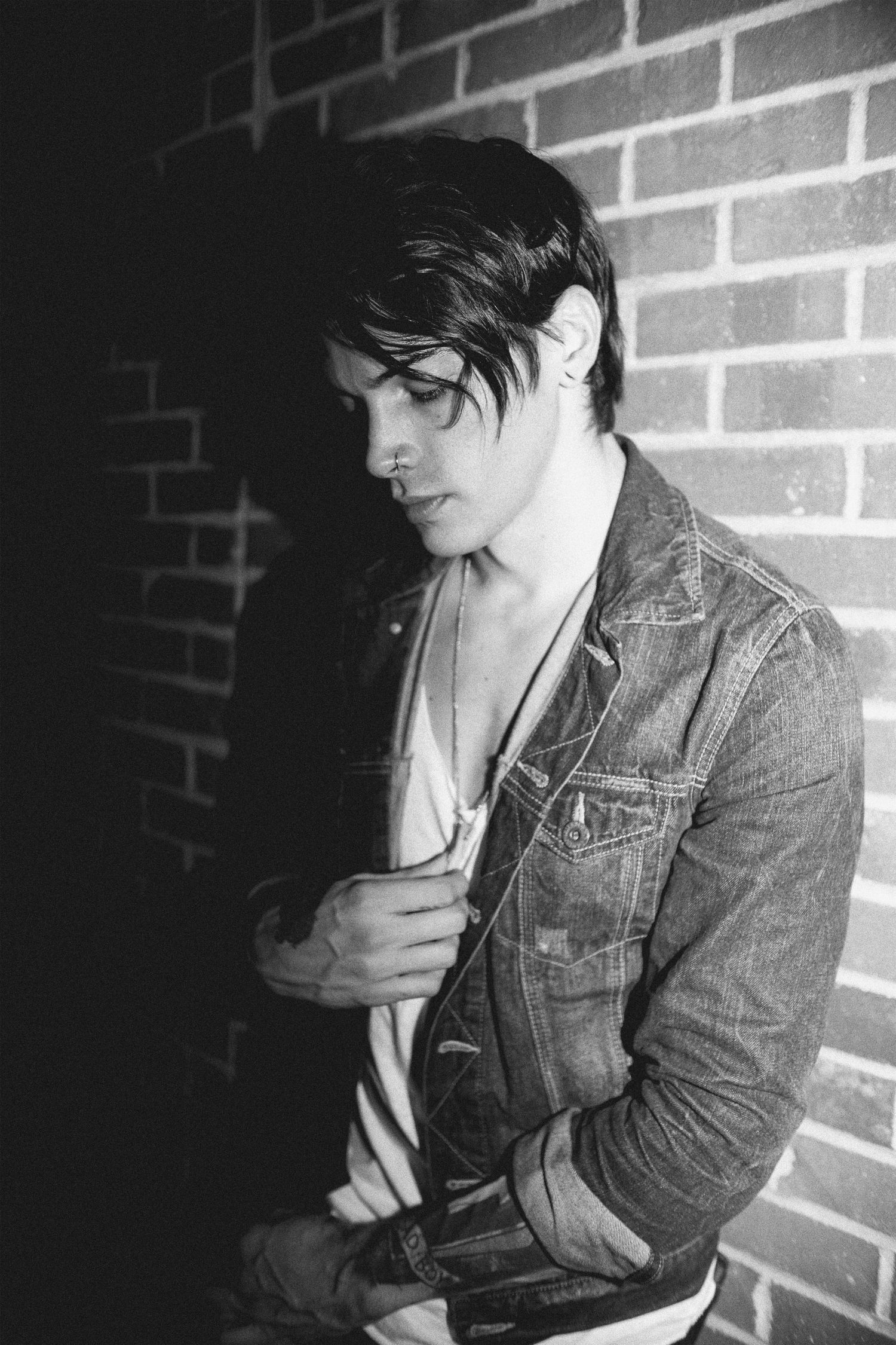 Black and white portrait series against brick wall showing moody artistic poses in denim jacket.