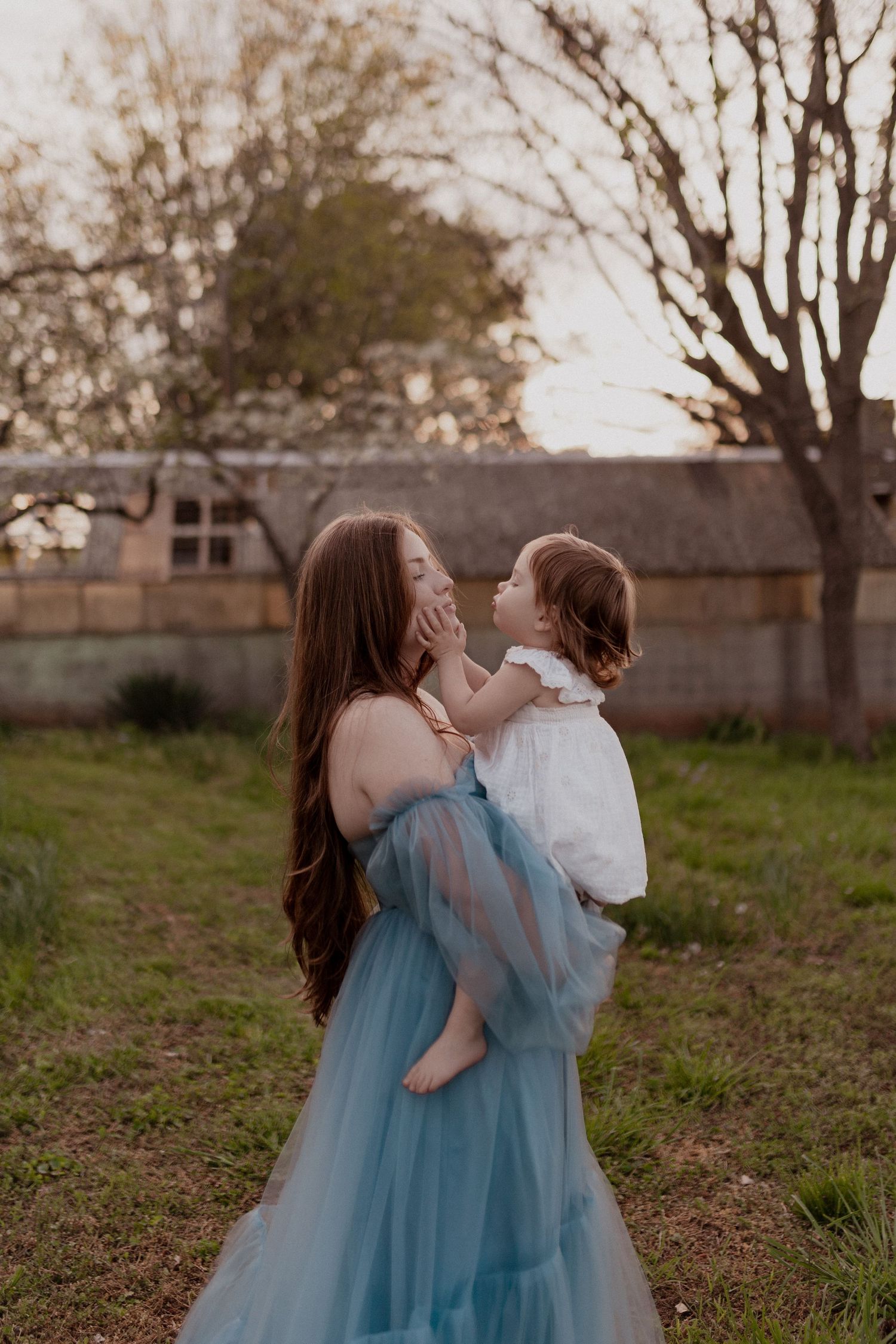 Two figures in flowing dresses share an intimate dance in a natural outdoor setting.
