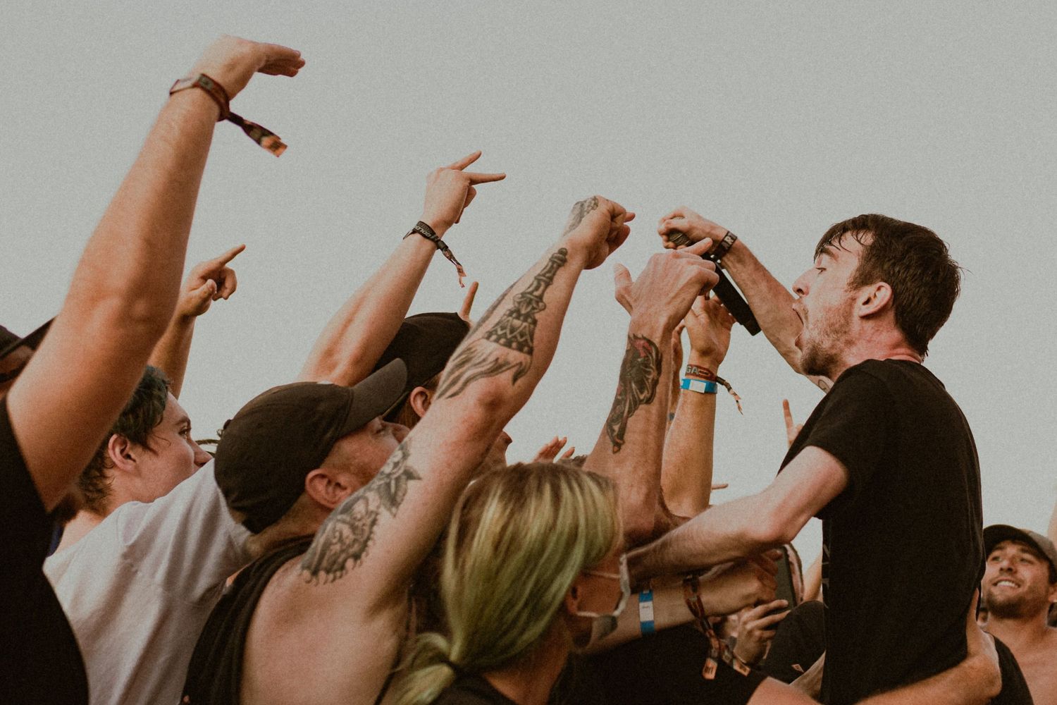 Concert crowd raises hands in unison during an energetic live music performance.