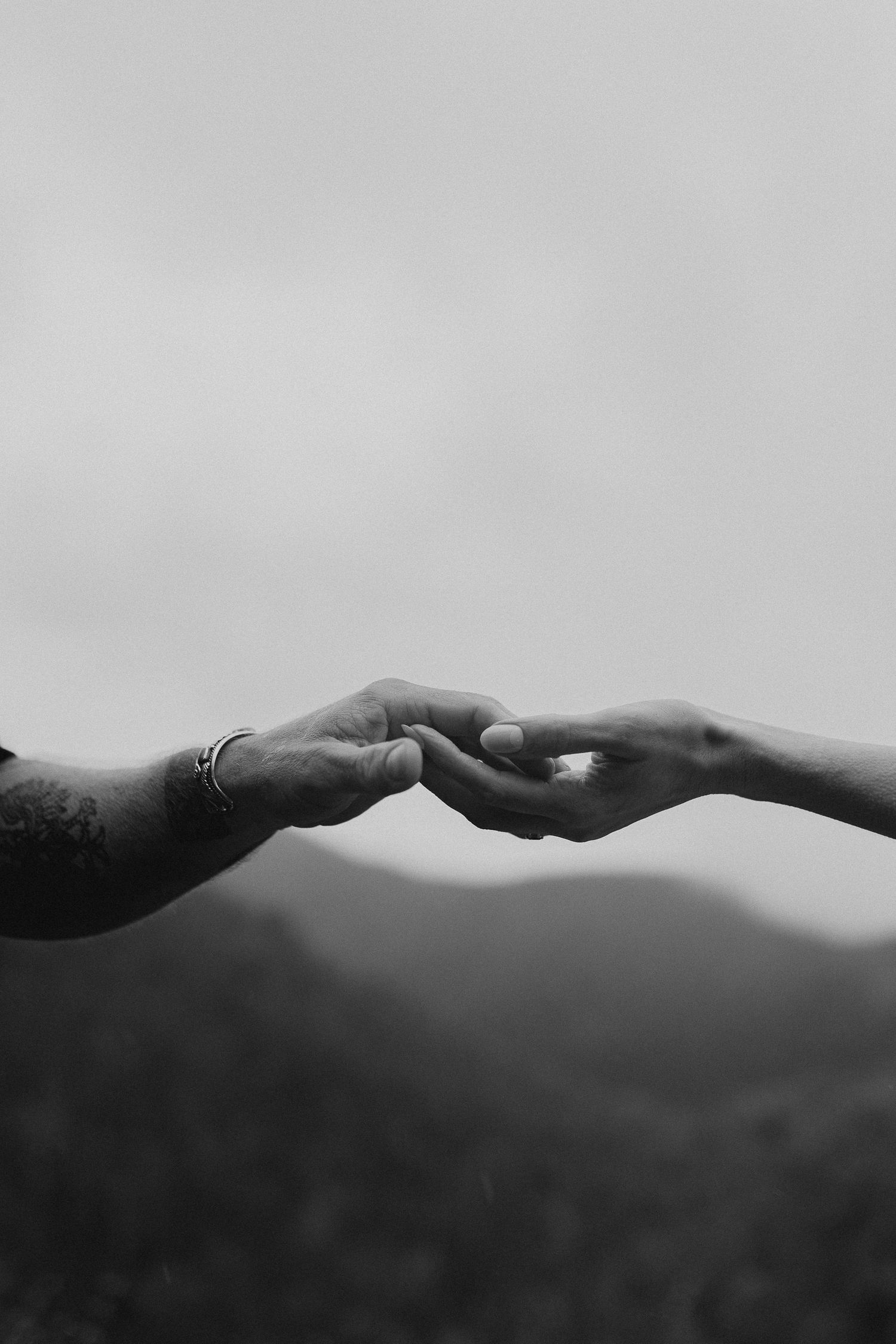 An artistic black and white silhouette of mountains against a misty sky.