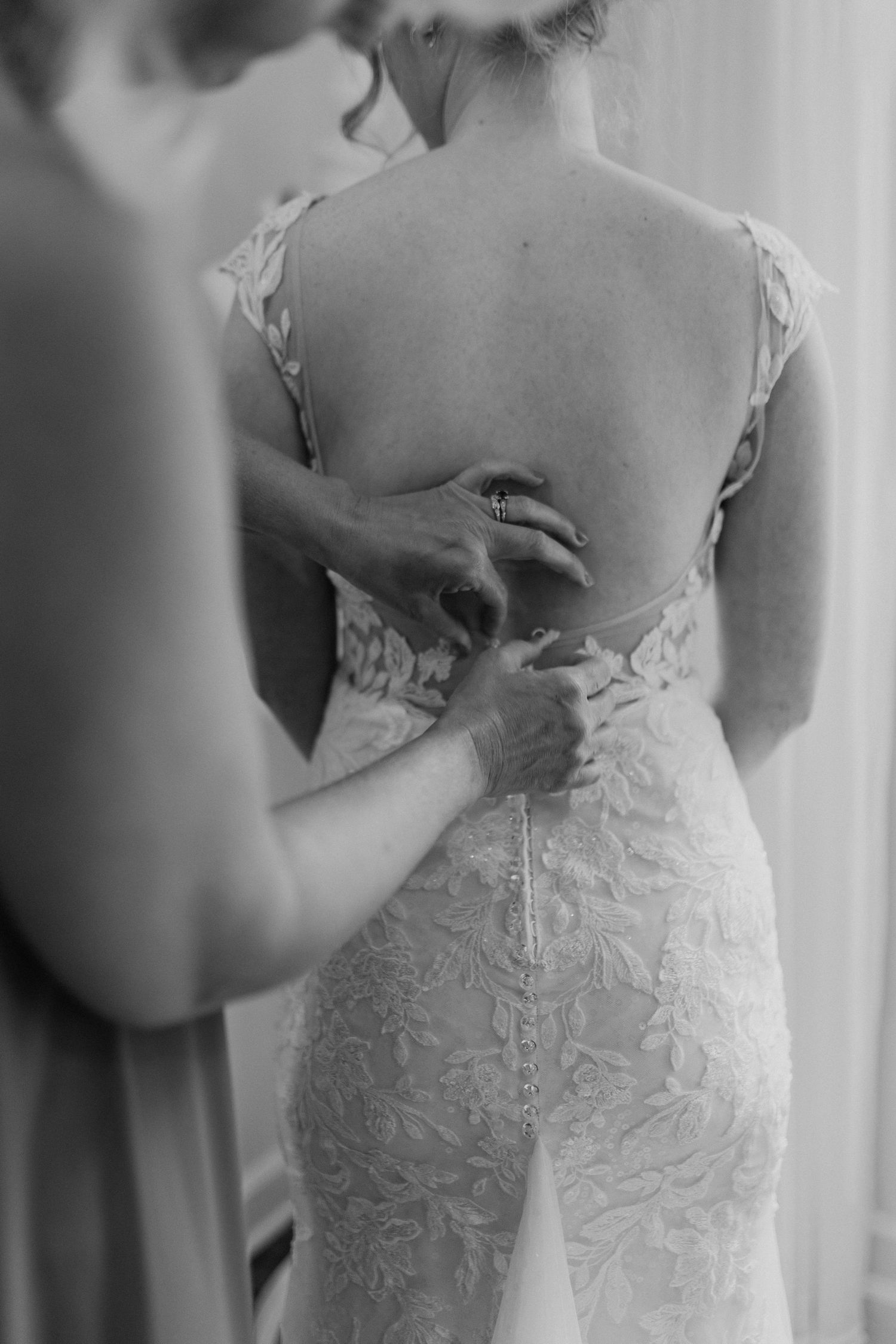 Close-up detail of intricate lace buttons on the back of a white wedding dress.