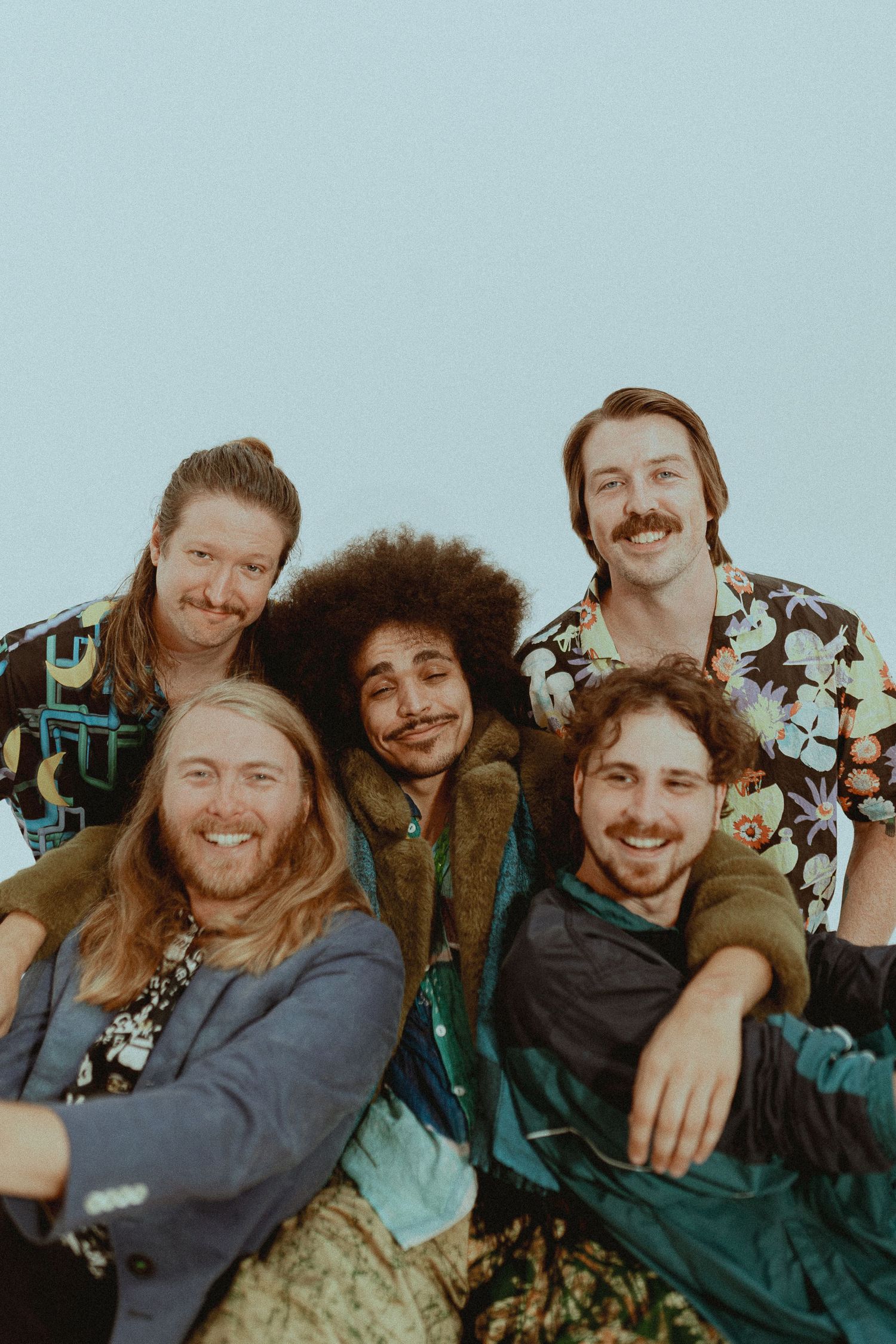 Candid group portrait with friends laughing and embracing in casual clothing.