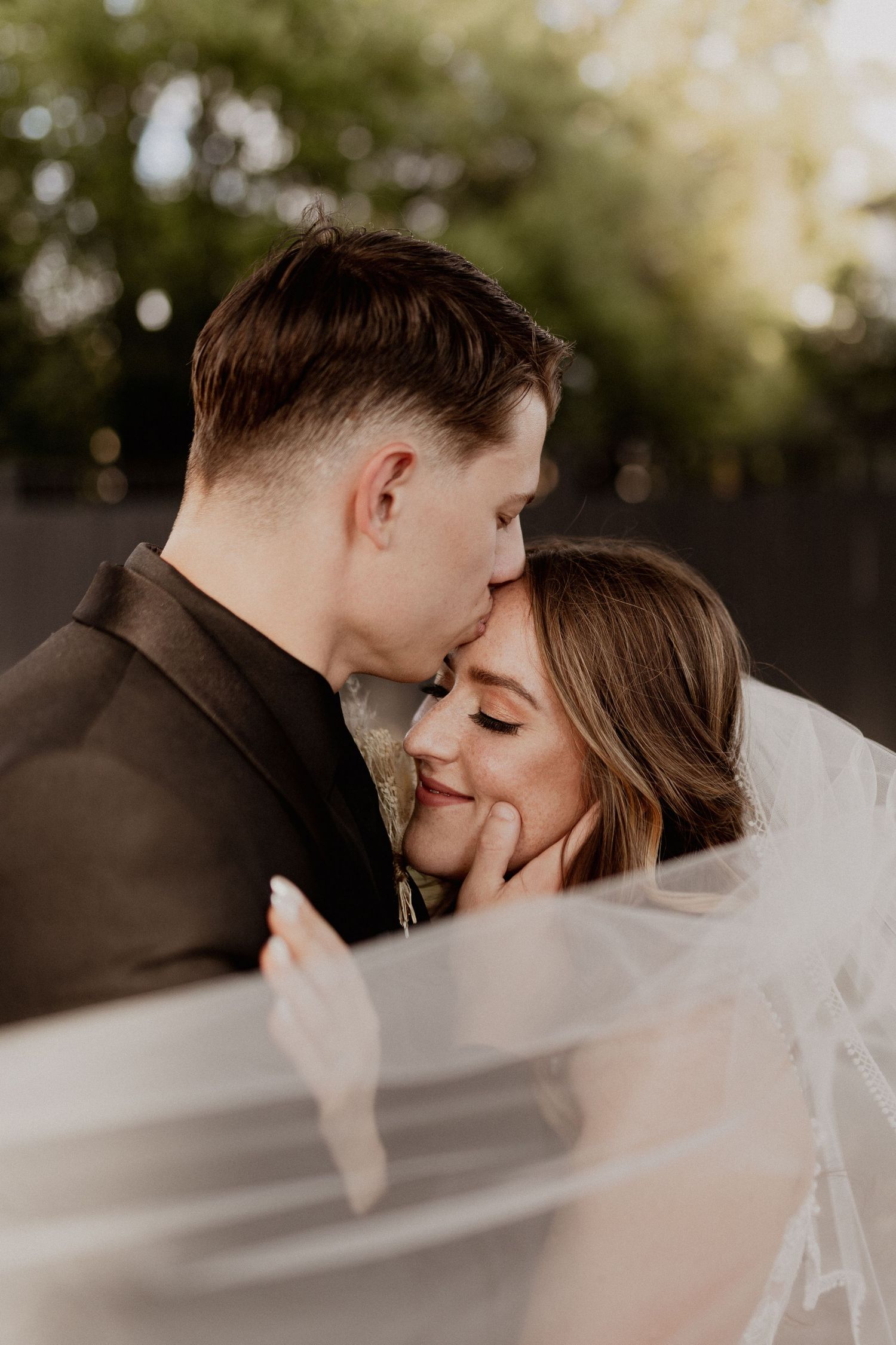 Intimate wedding portrait with soft lighting and flowing veil creating romantic atmosphere.