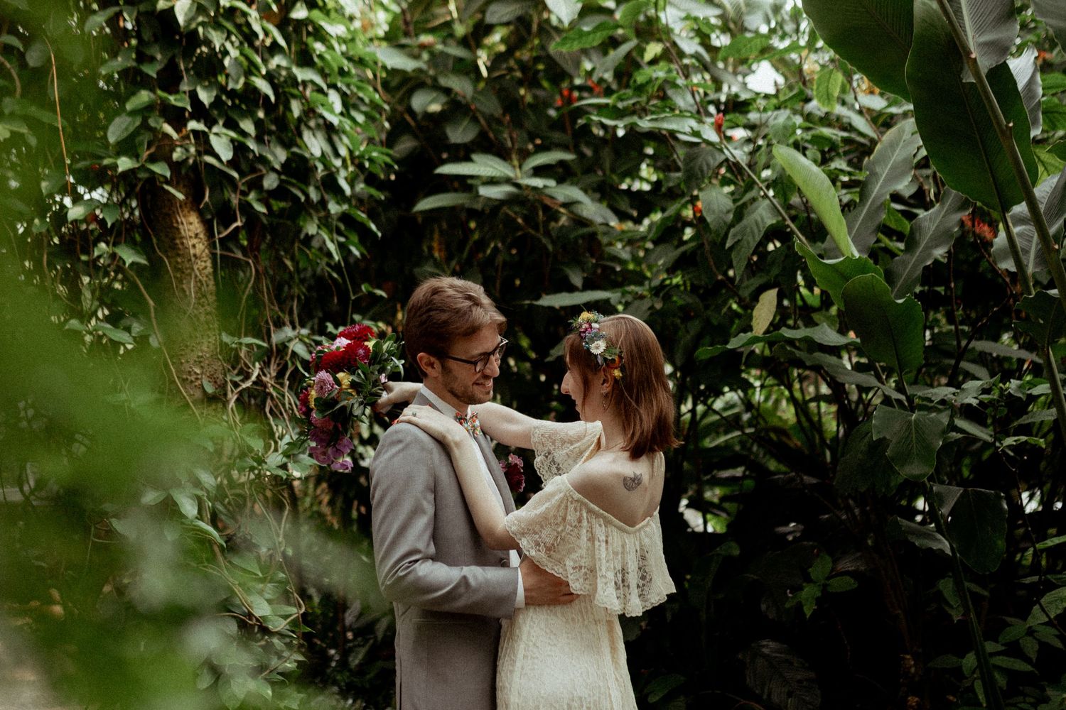 Wedding couple sharing tender moments among greenhouse greenery and flowers.