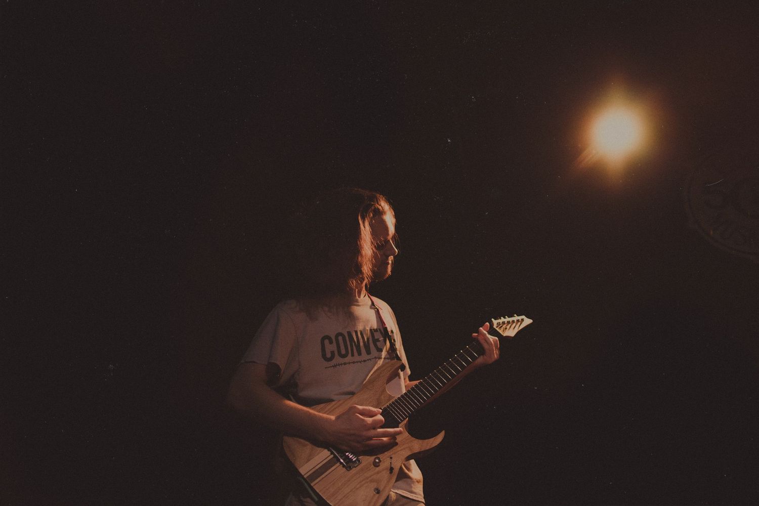 Musicians performing on a dimly lit stage with moody atmospheric lighting.