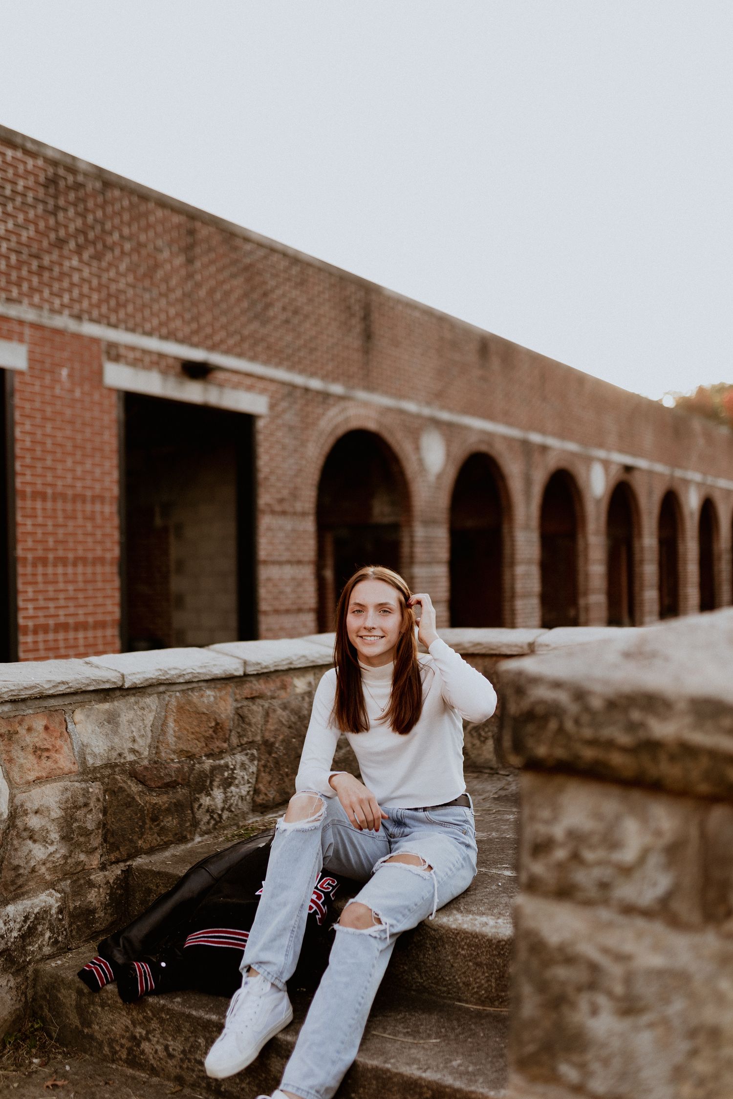 Portrait session against brick architecture with arched colonnade creating leading lines.