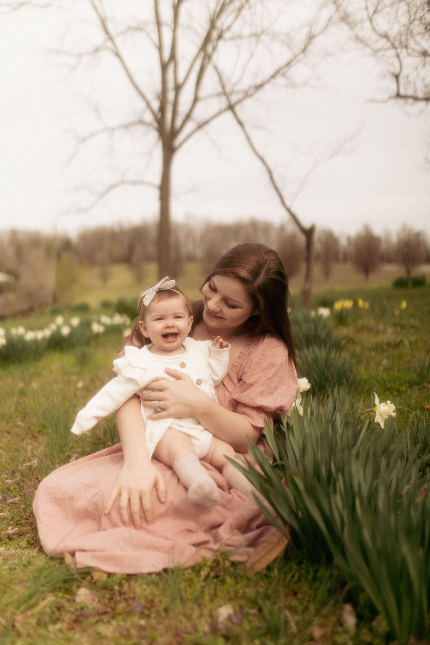 A springtime outdoor photoshoot with pink dresses and blooming daffodils in a natural garden setting.