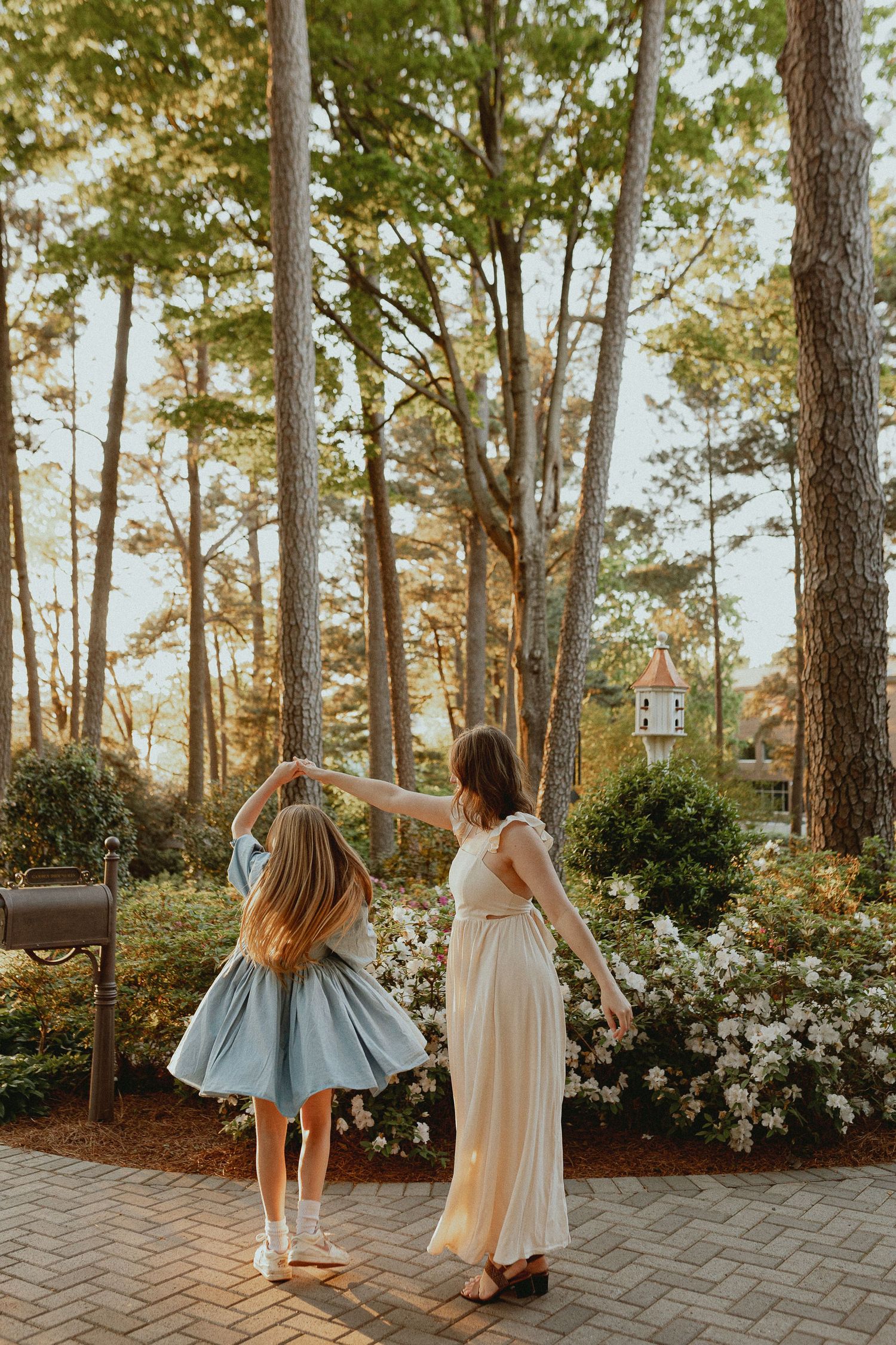 Dancing and twirling on a brick patio surrounded by tall pine trees and white azaleas.