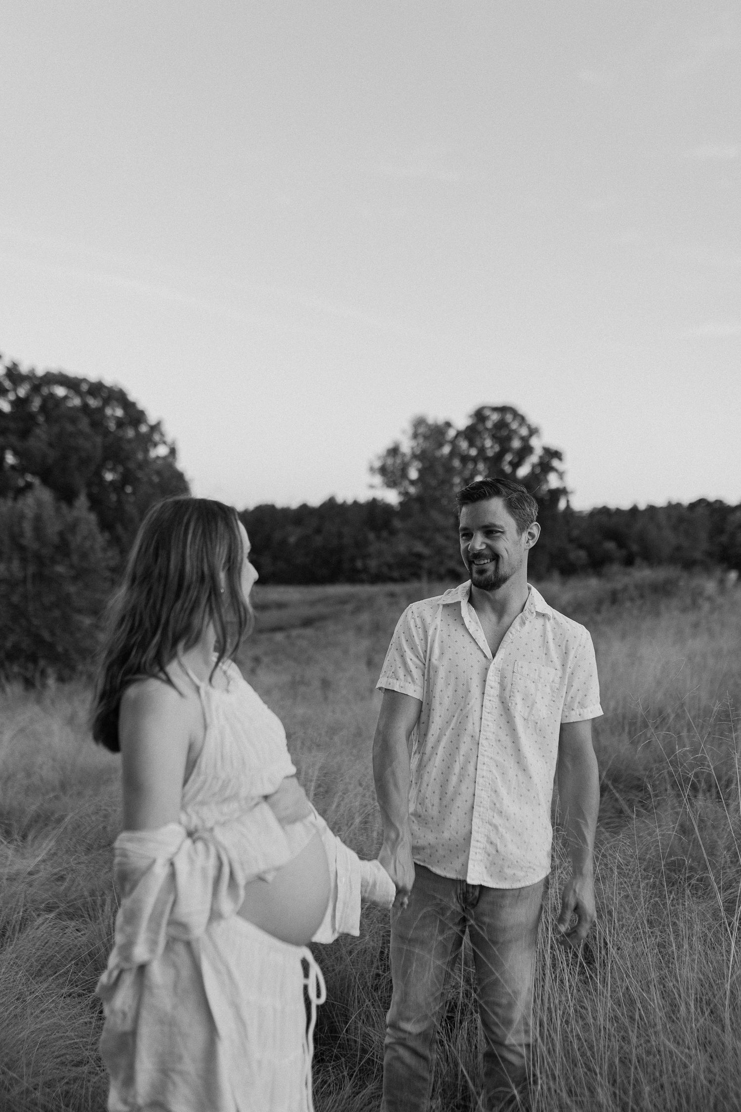 Maternity photoshoot in a rustic field setting at golden hour.