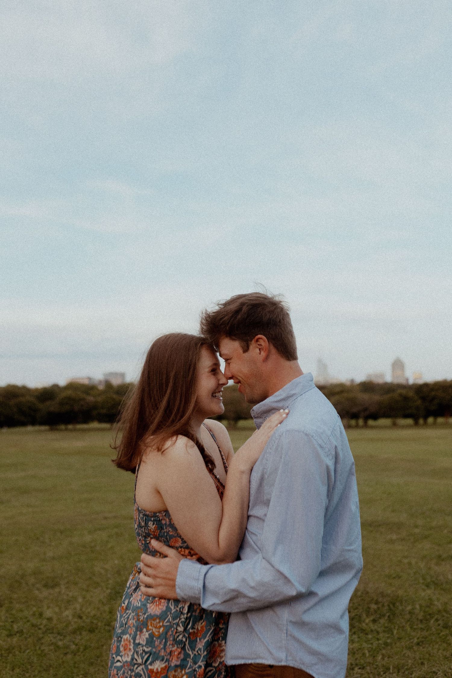 A couple shares an intimate moment in an open field during golden hour.