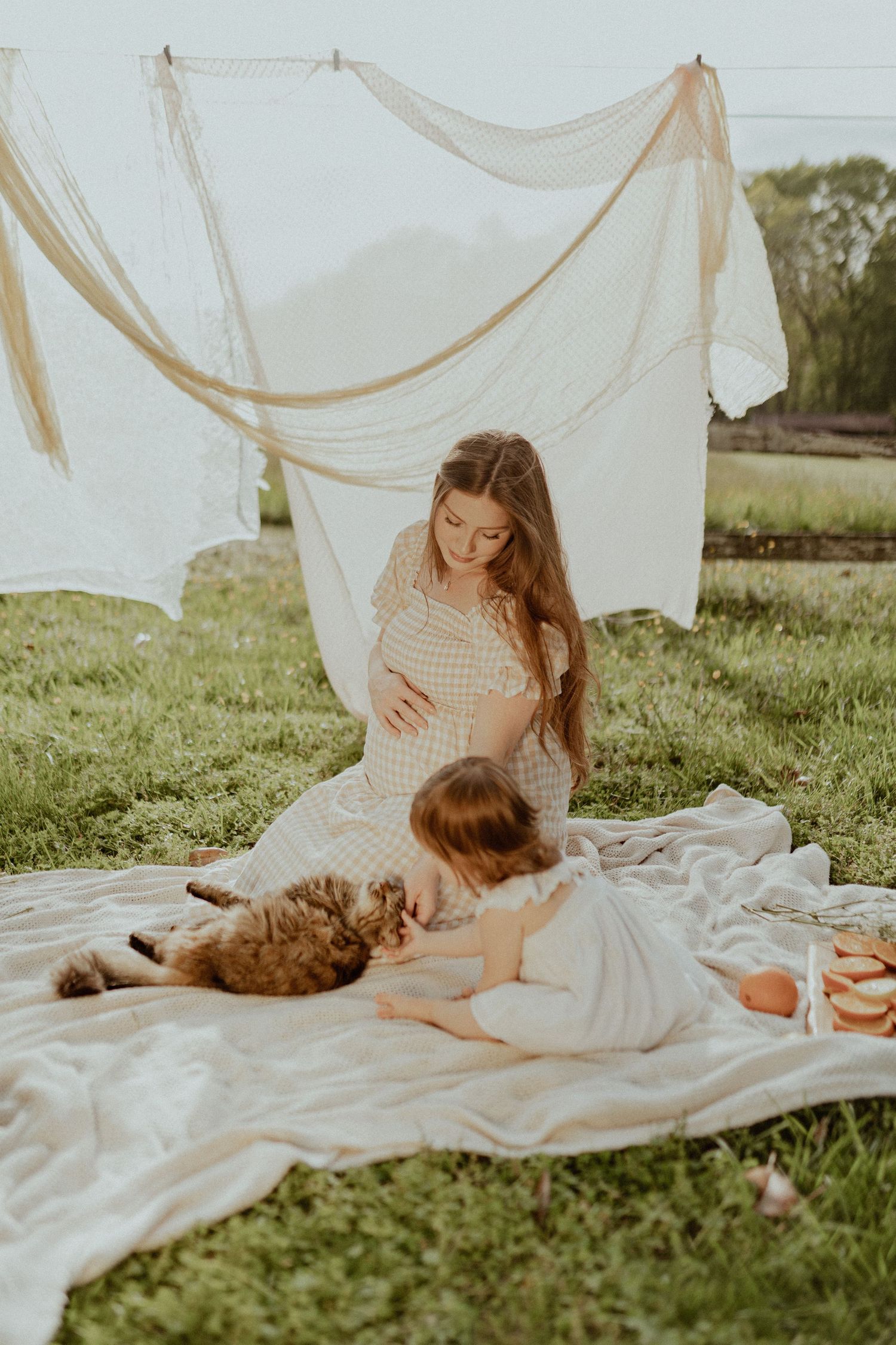 A sunny outdoor picnic setting with white hanging linens and a relaxed atmosphere.