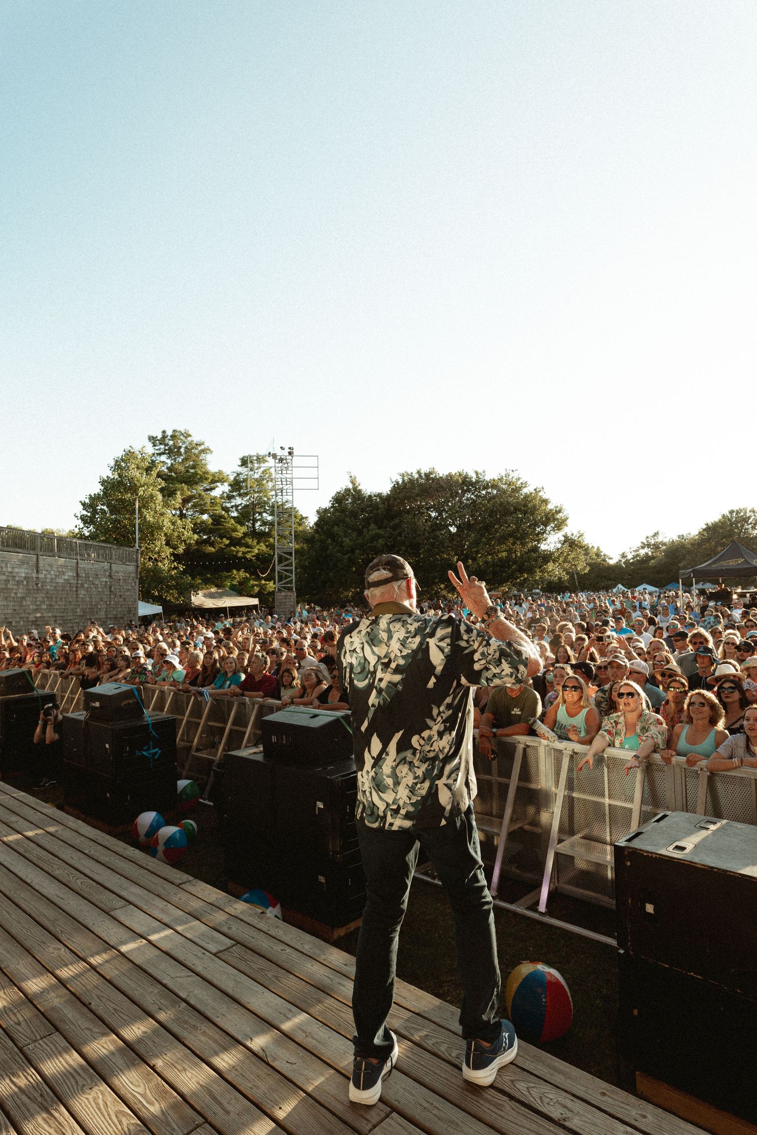 Large outdoor concert crowd gathered in front of a stage during a daytime performance.
