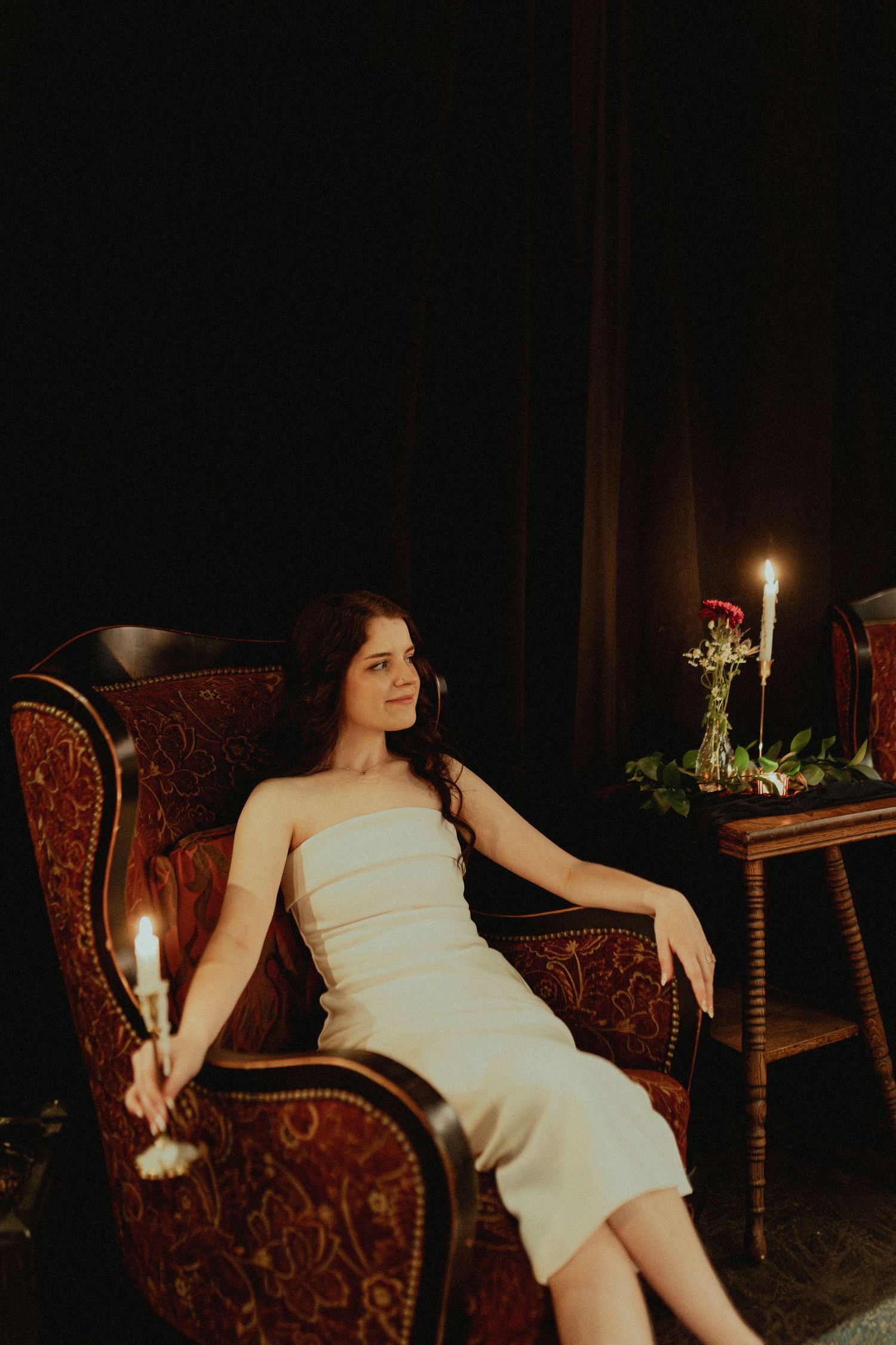 Candlelit scene with vintage velvet chair in dark moody setting.