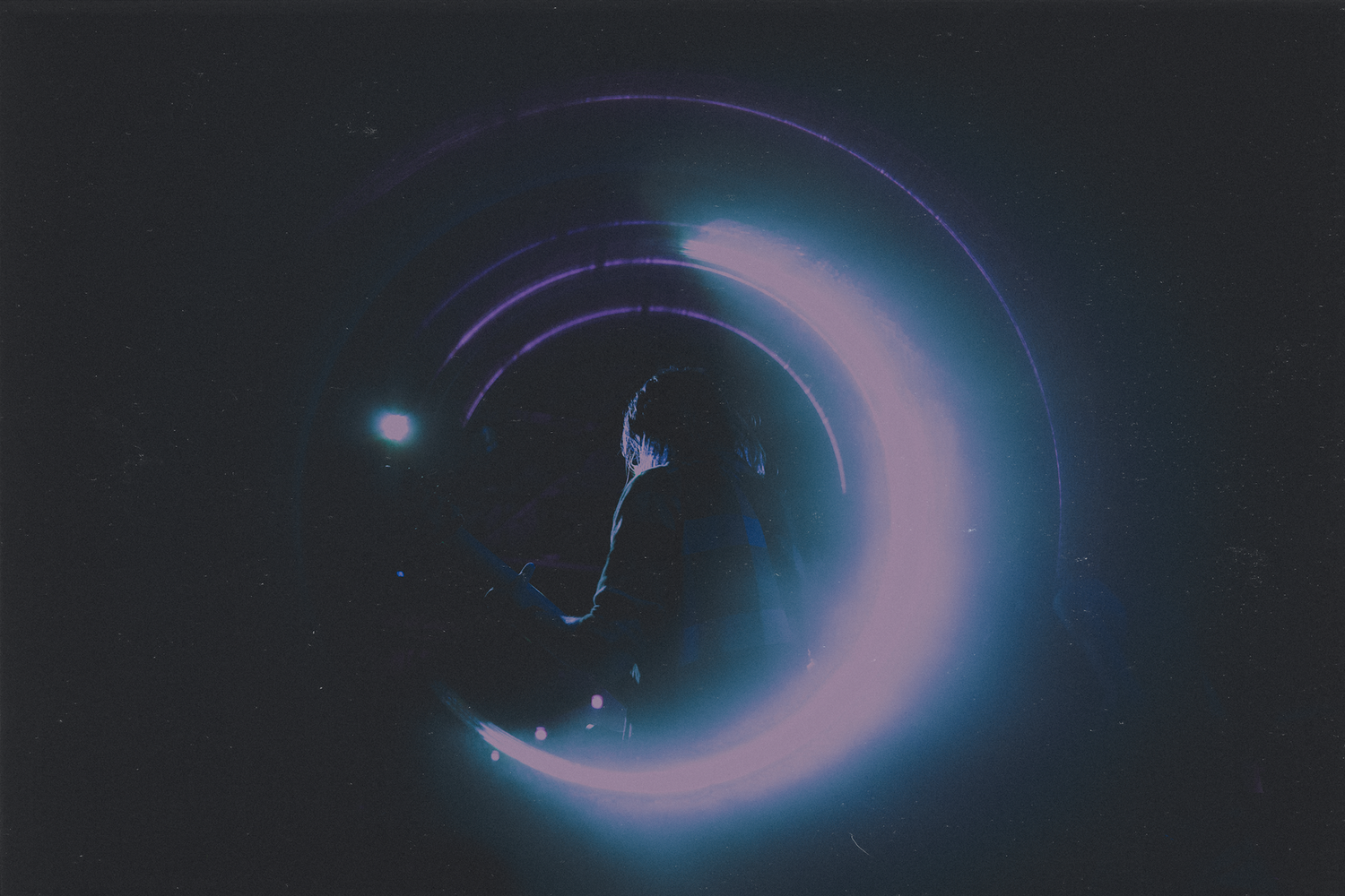 Abstract artistic photo showing a crescent moon shape with blue and pink ethereal lighting effects.
