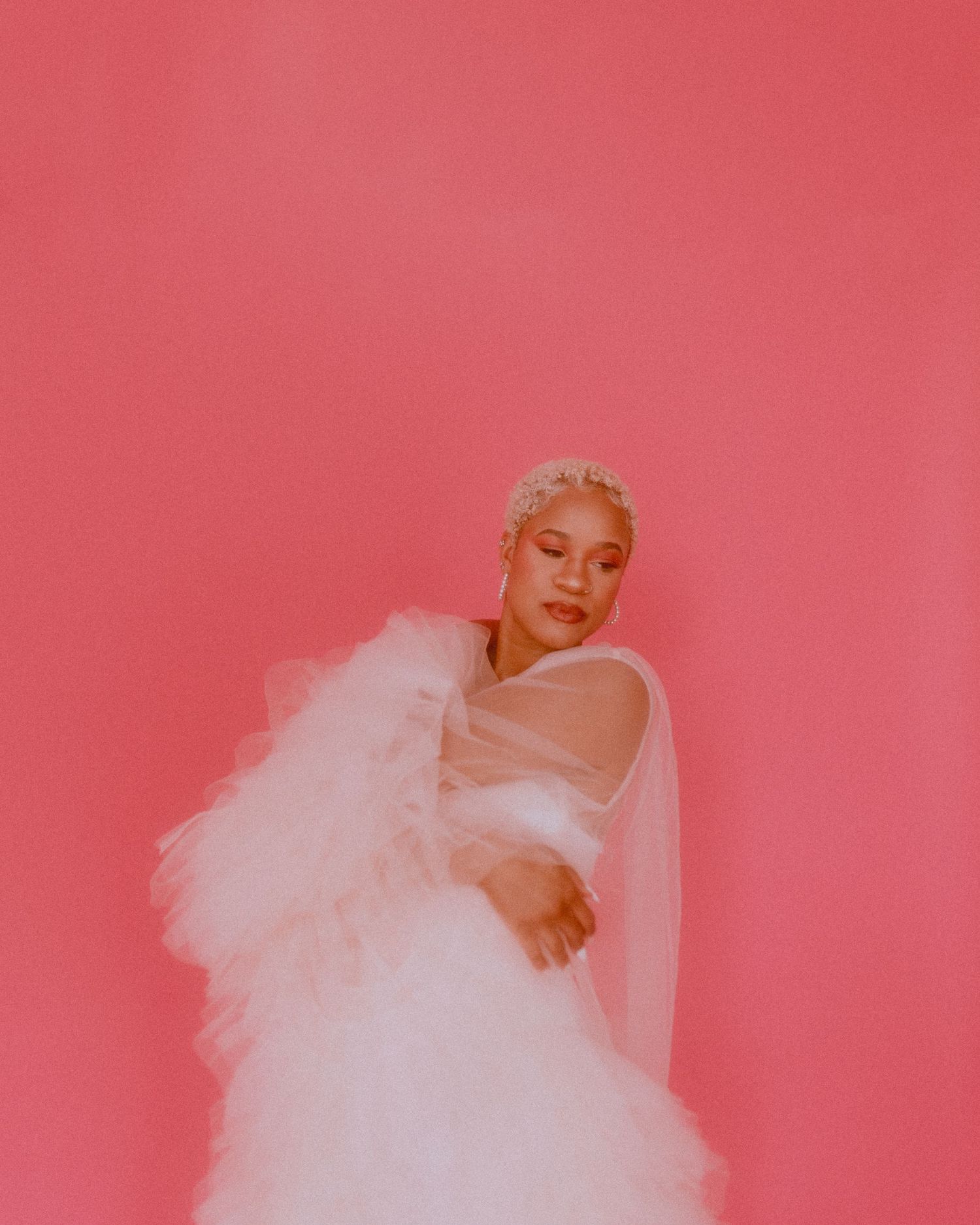 Ethereal fashion portraits with flowing white tulle against pink studio backdrop.