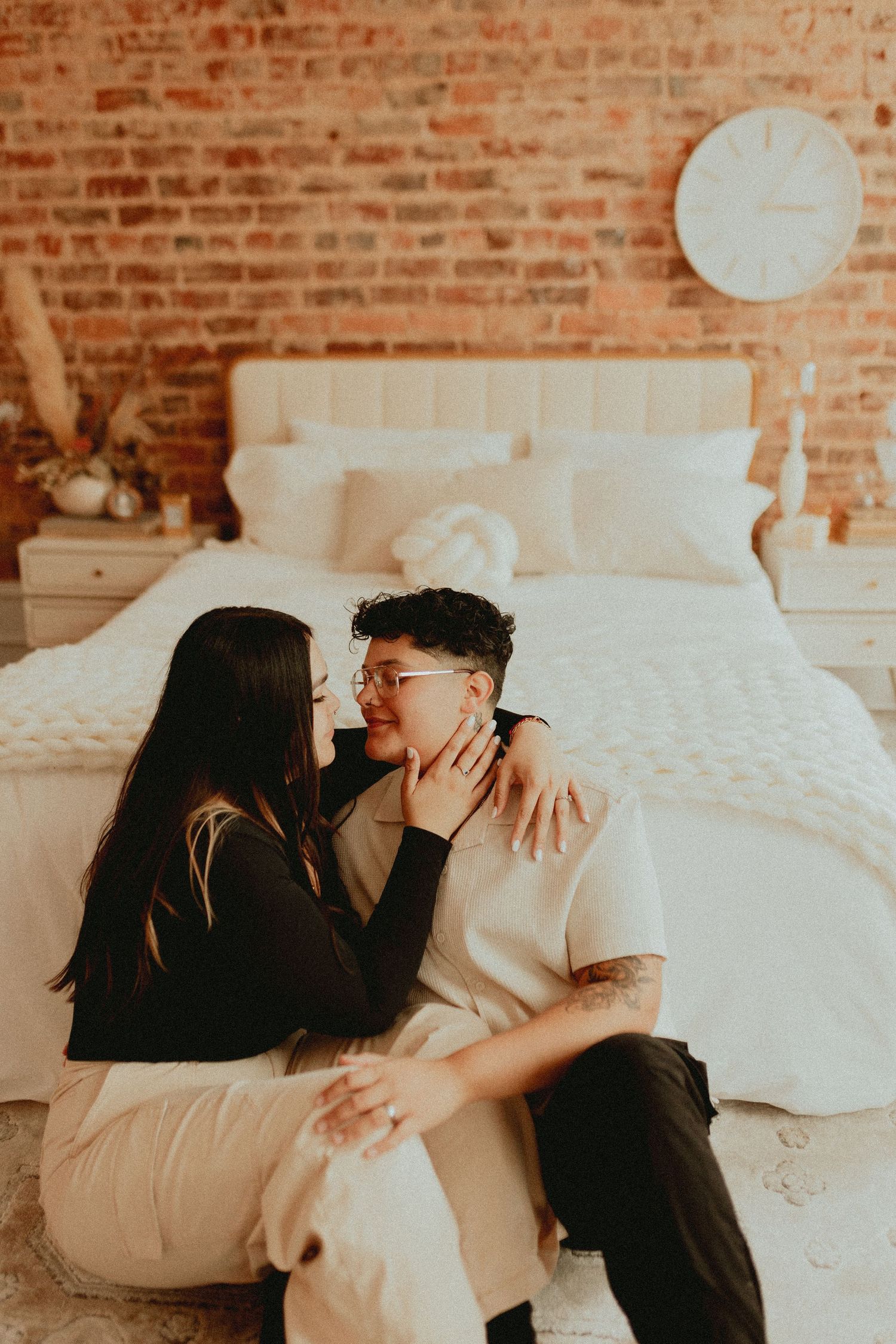 A series of tender moments captured on a bed with exposed brick wall backdrop.