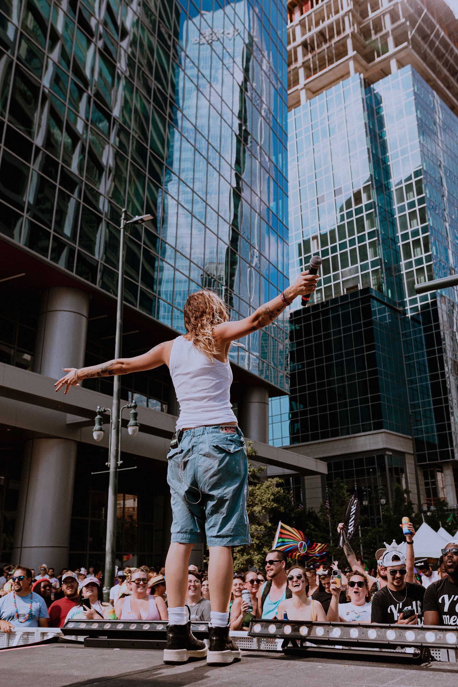 Skateboarder performing tricks in front of a modern glass office building with crowd watching.