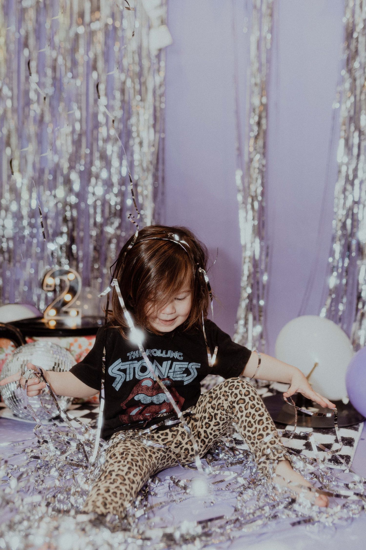 Playful glitter photo session with sparkly decorations and silver tinsel backdrop.
