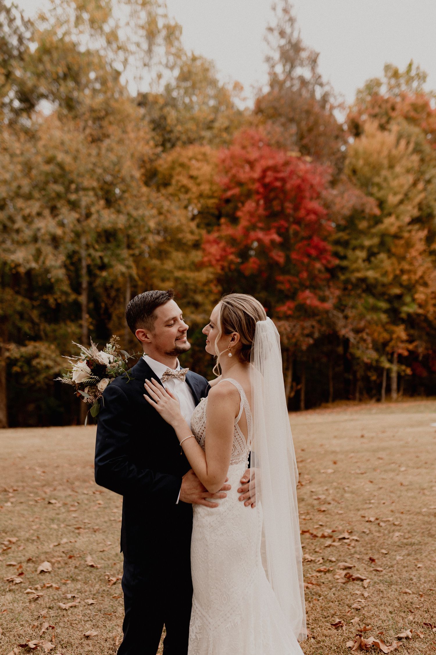 A couple celebrates their wedding day surrounded by vibrant fall foliage.