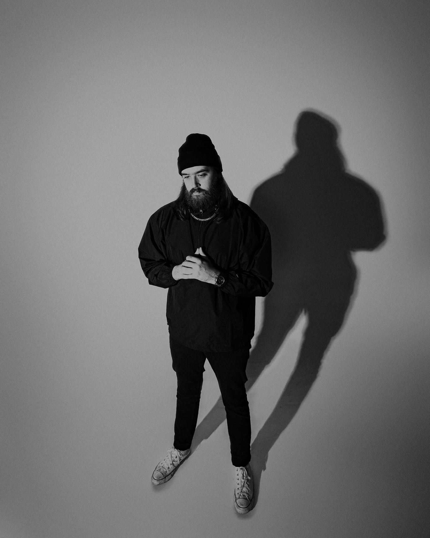 Black and white artistic portrait with dramatic shadows against a gray background.